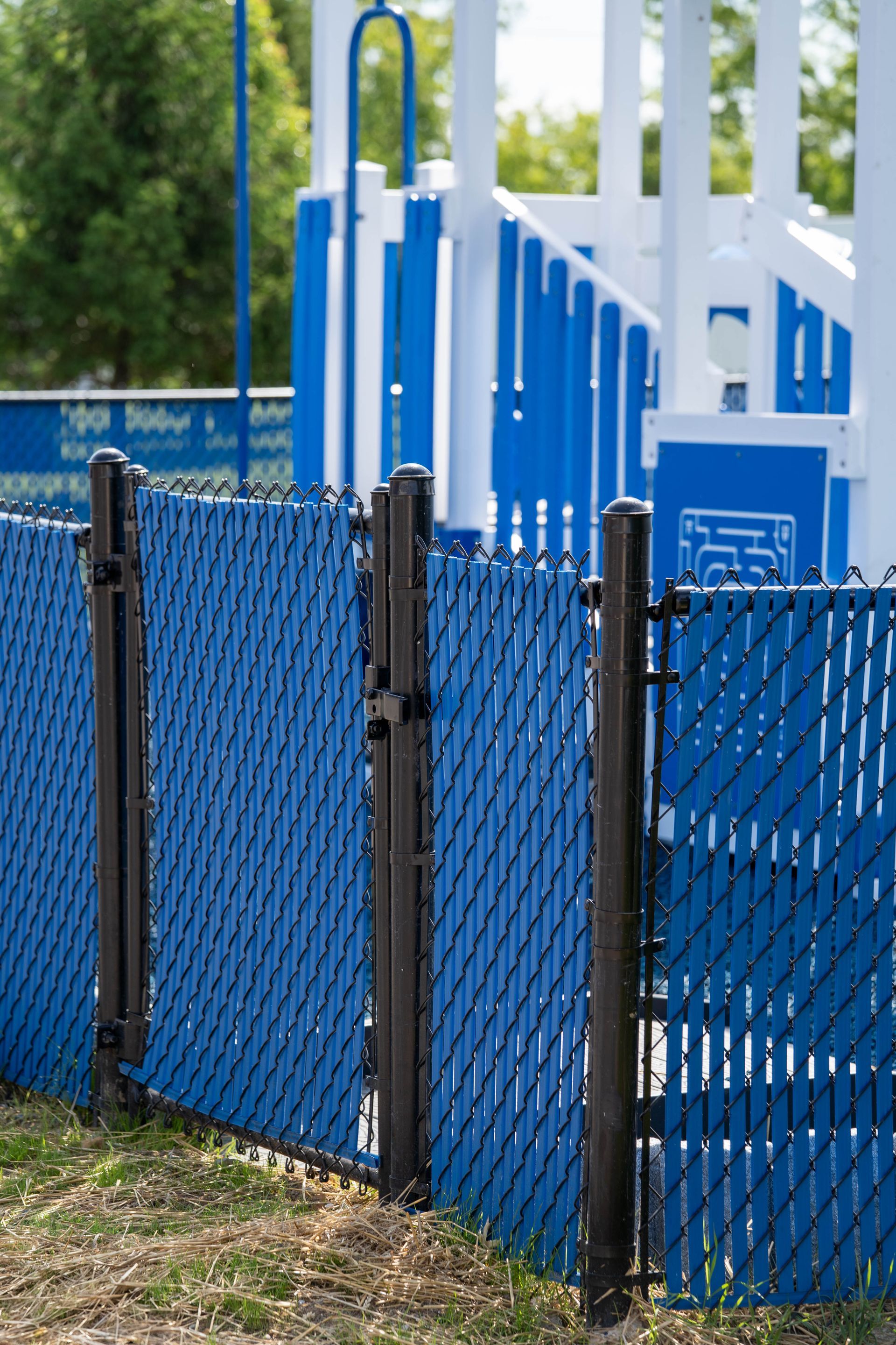 Blue chain-link fence in front of a blue and white playground structure.