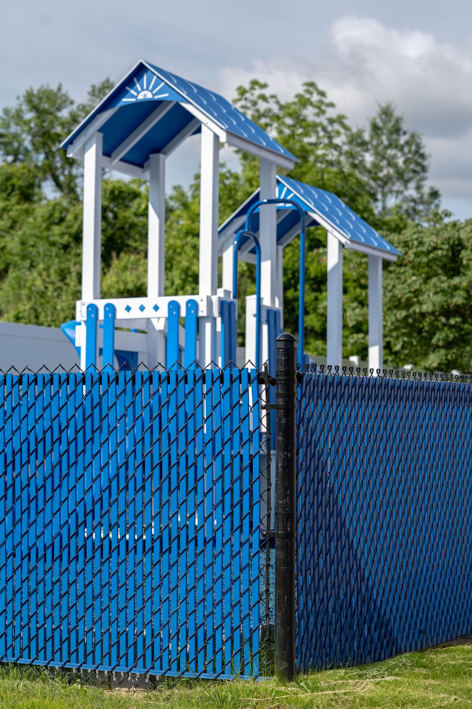 Blue and white playground structure with a blue fence.