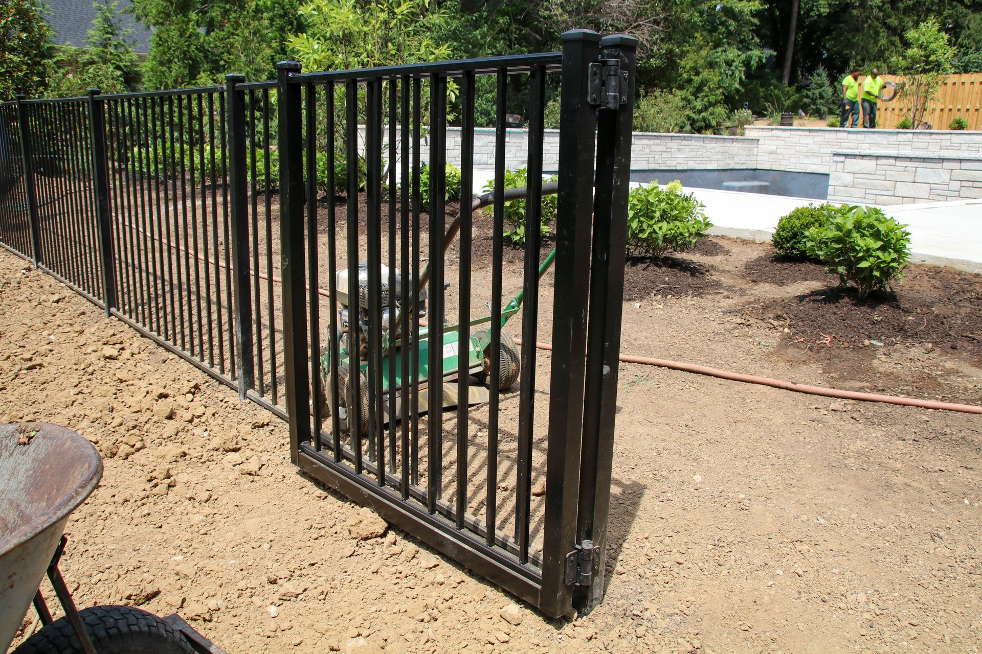 Black metal fence with gate, bordering a yard.