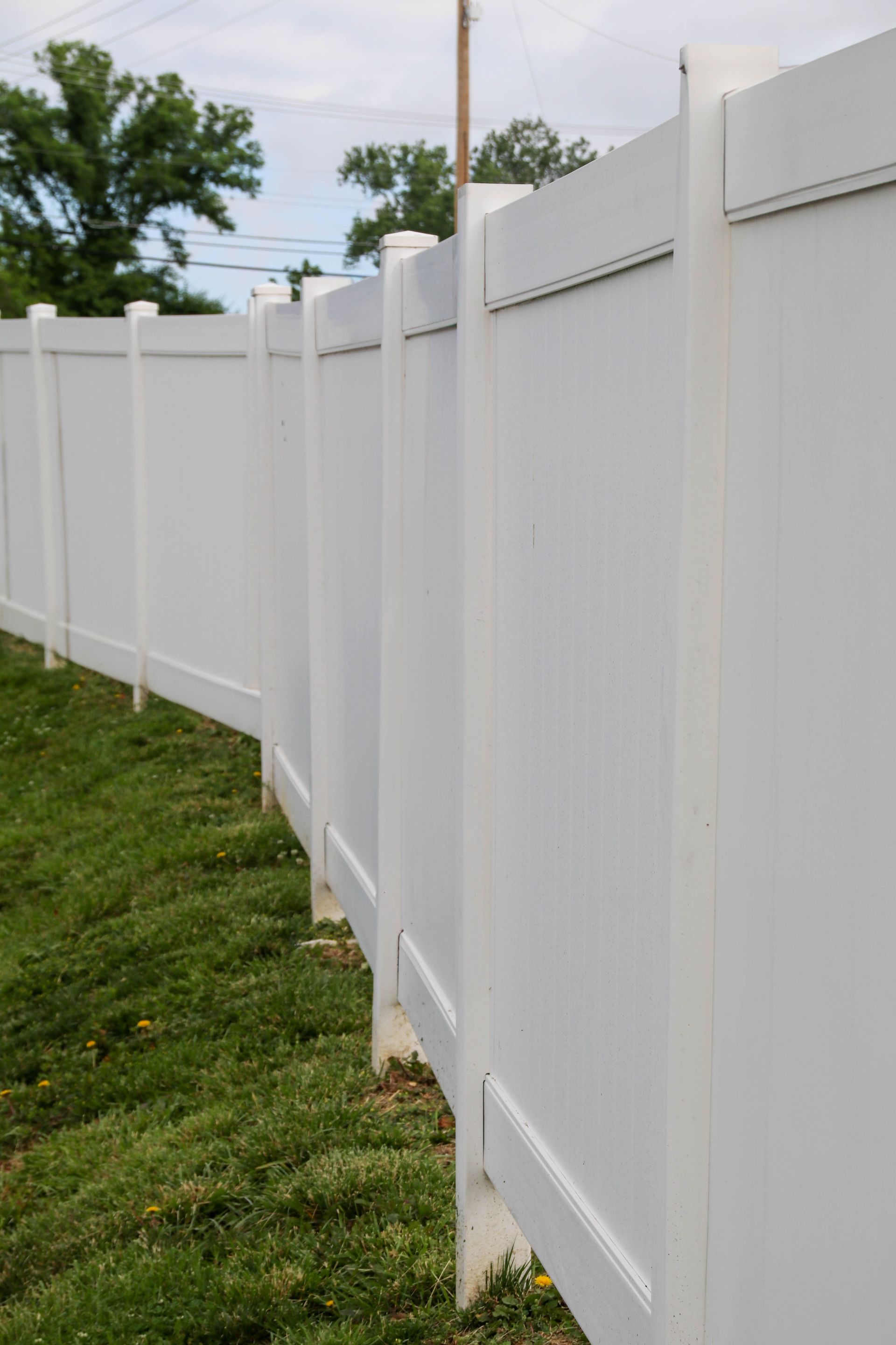 White vinyl privacy fence in a grassy yard.