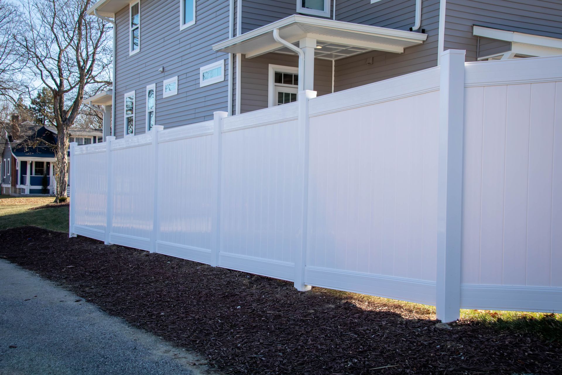 White vinyl fence alongside a house and a path.