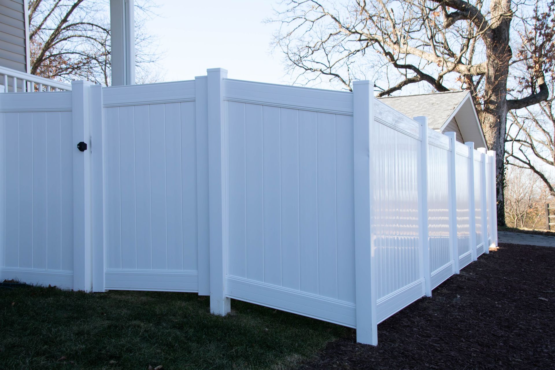 White vinyl privacy fence in a yard.