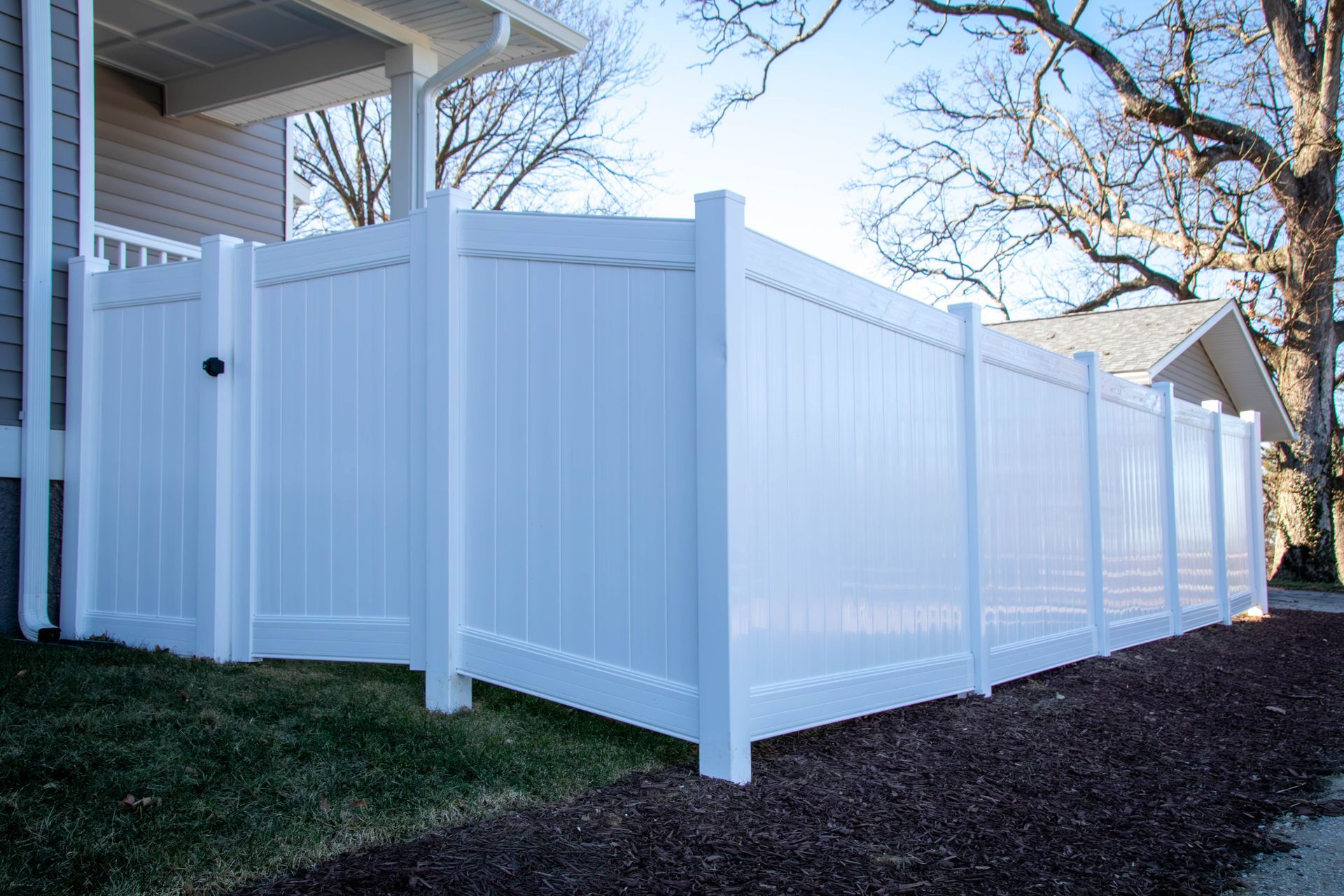 White vinyl privacy fence around a house.