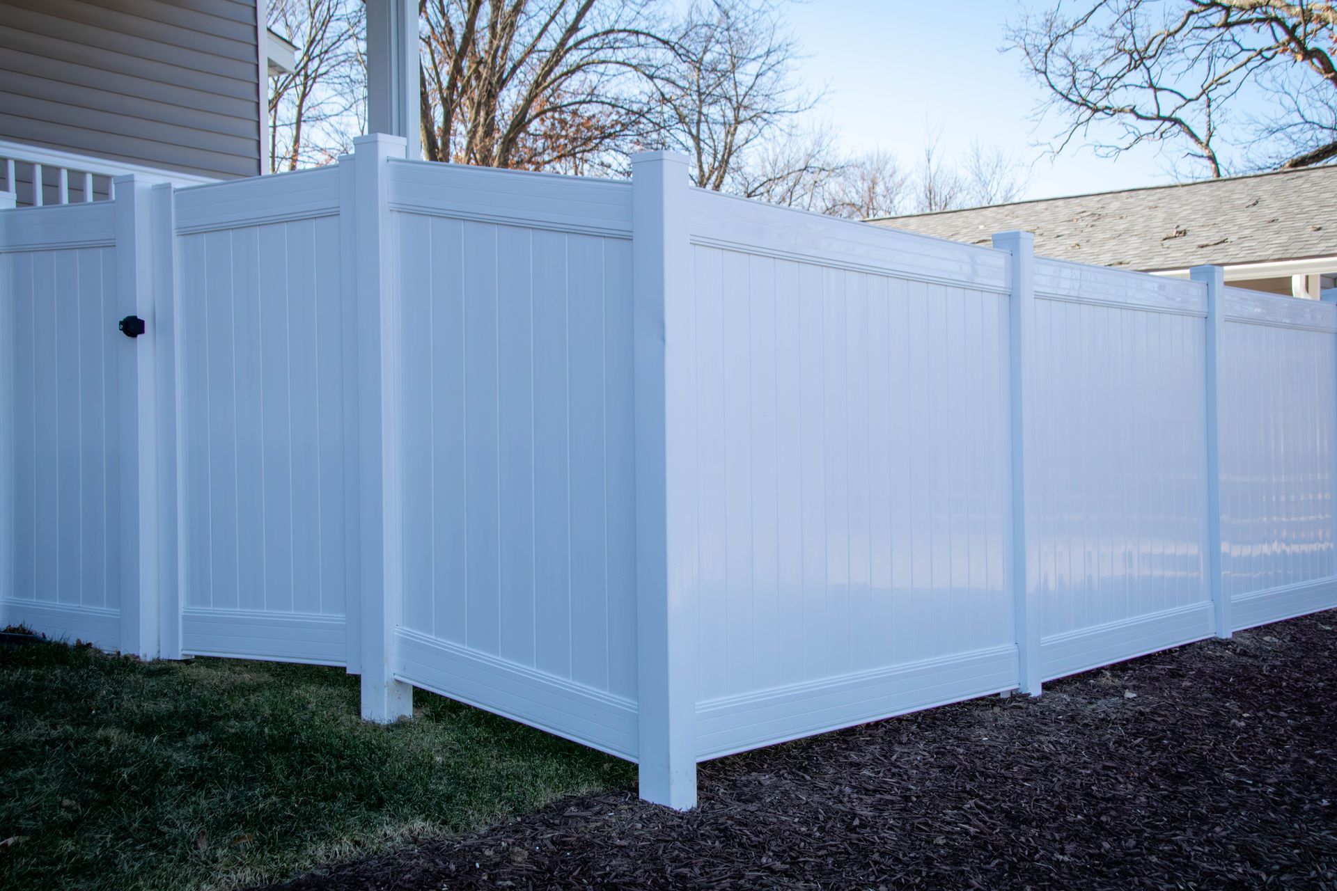 White vinyl privacy fence in a yard.