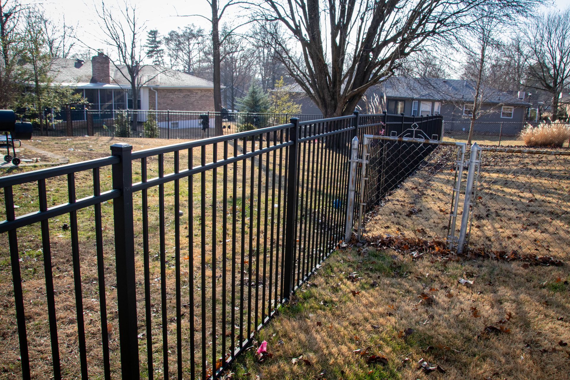 Black metal fence in a yard with houses in the background.