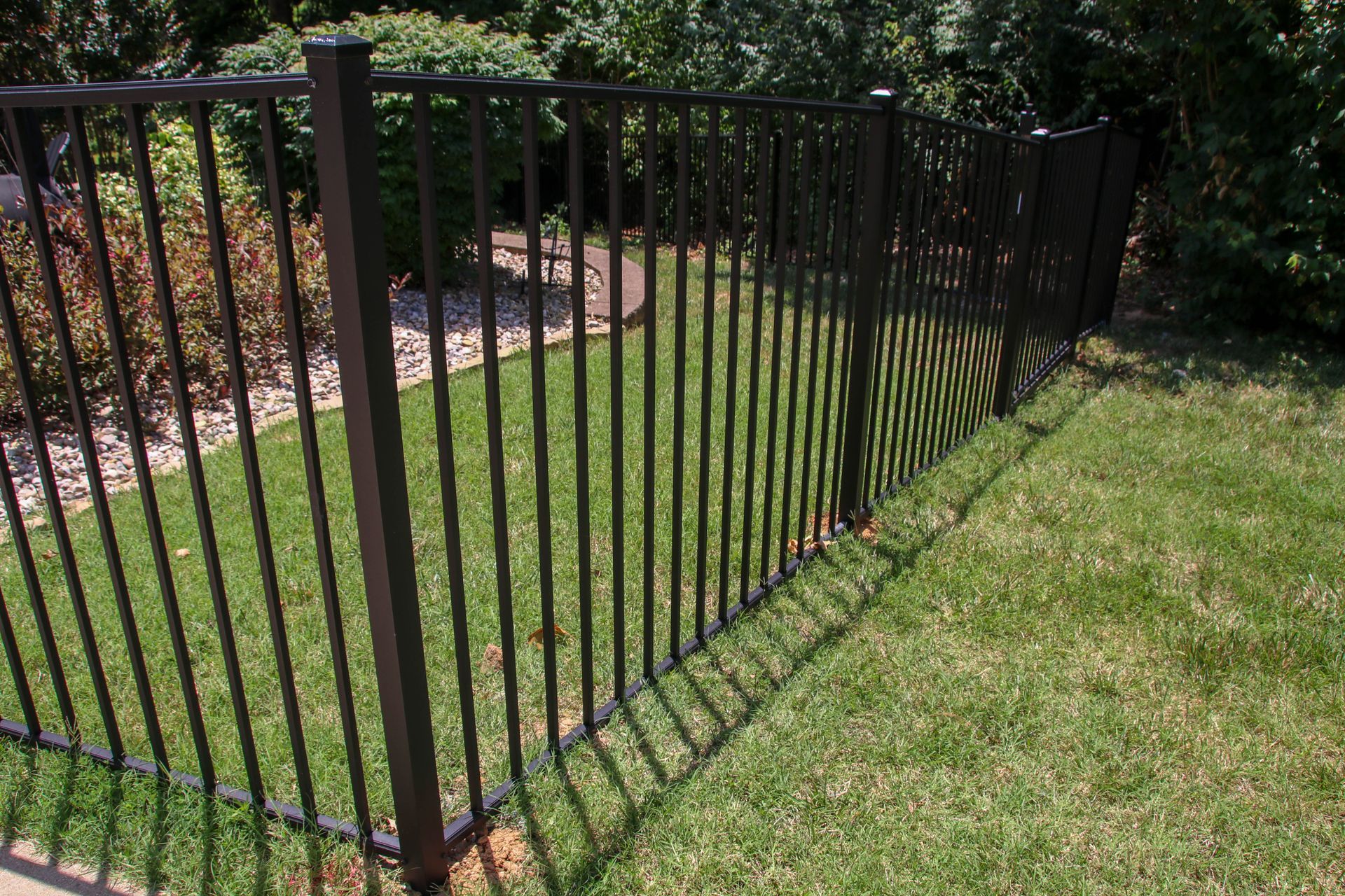 Black metal fence bordering a green lawn.