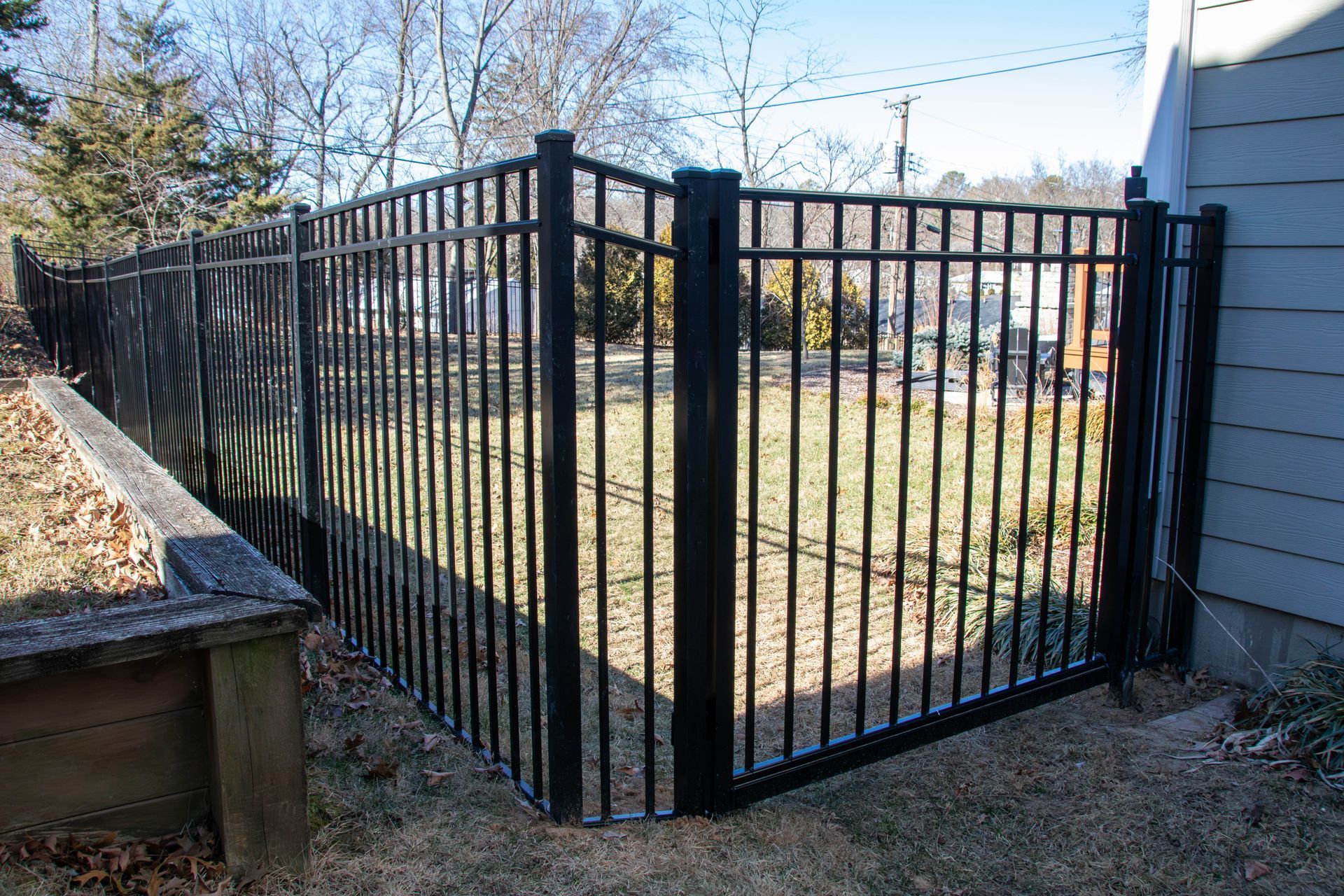 Black metal fence enclosing a small yard area next to a house.