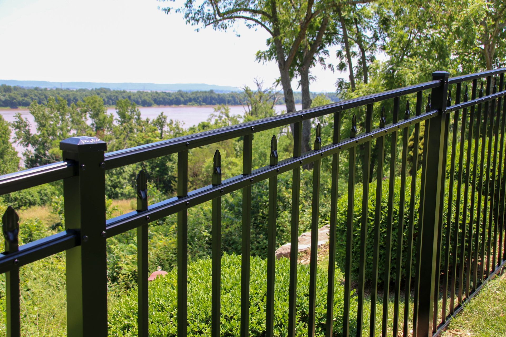 Black metal fence overlooking a river and trees.