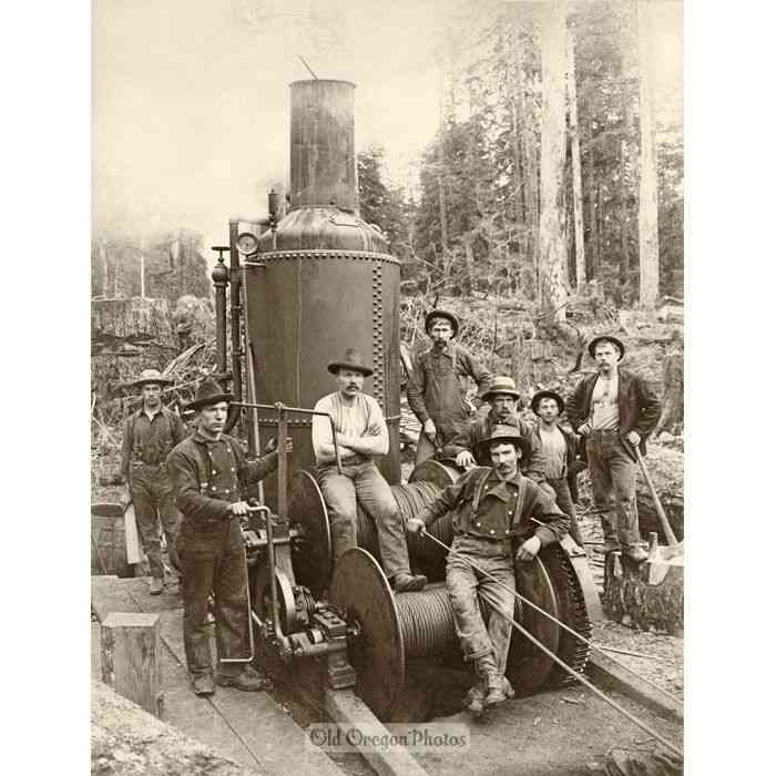 Group posing beside an early steam locomotive in a forest clearing