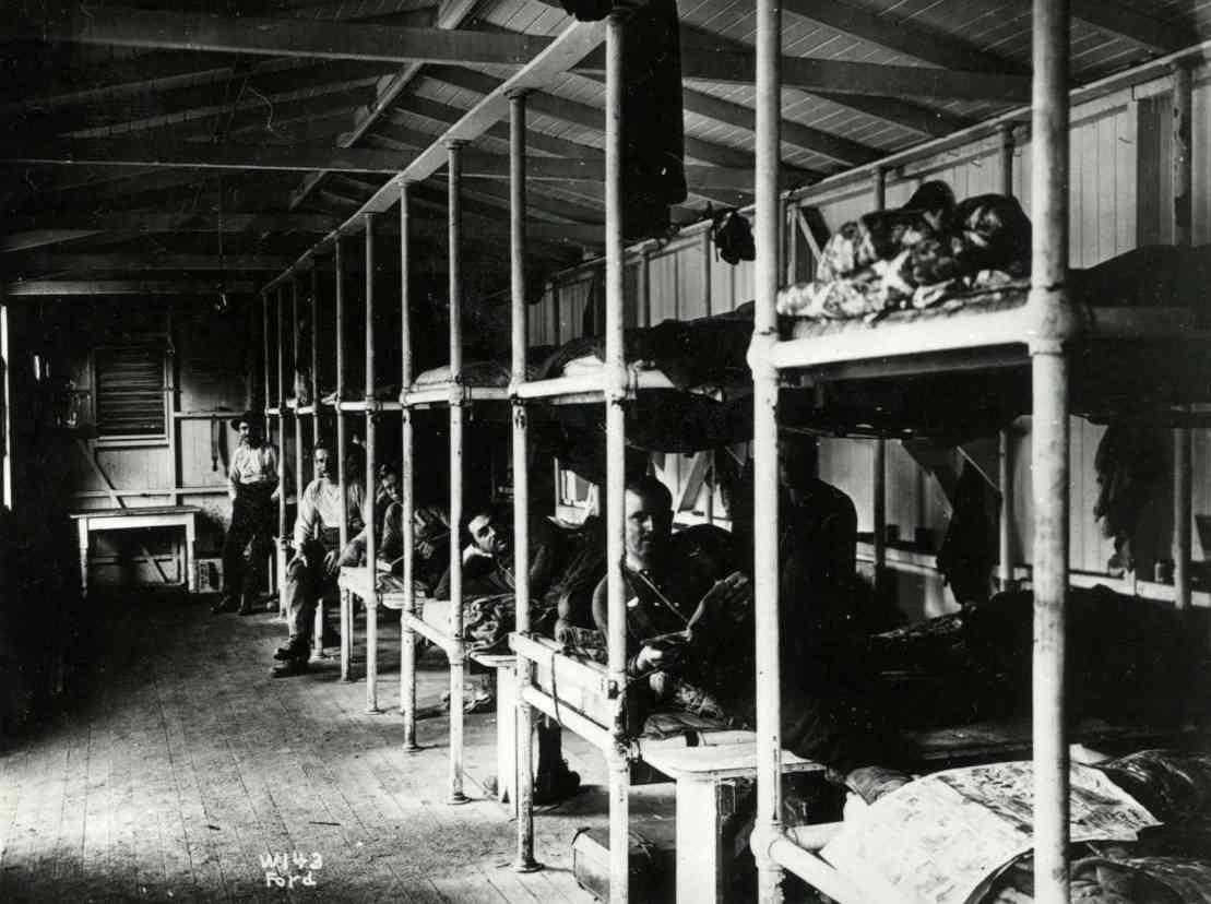 Dormitory with rows of bunk beds and people resting in a dimly lit room