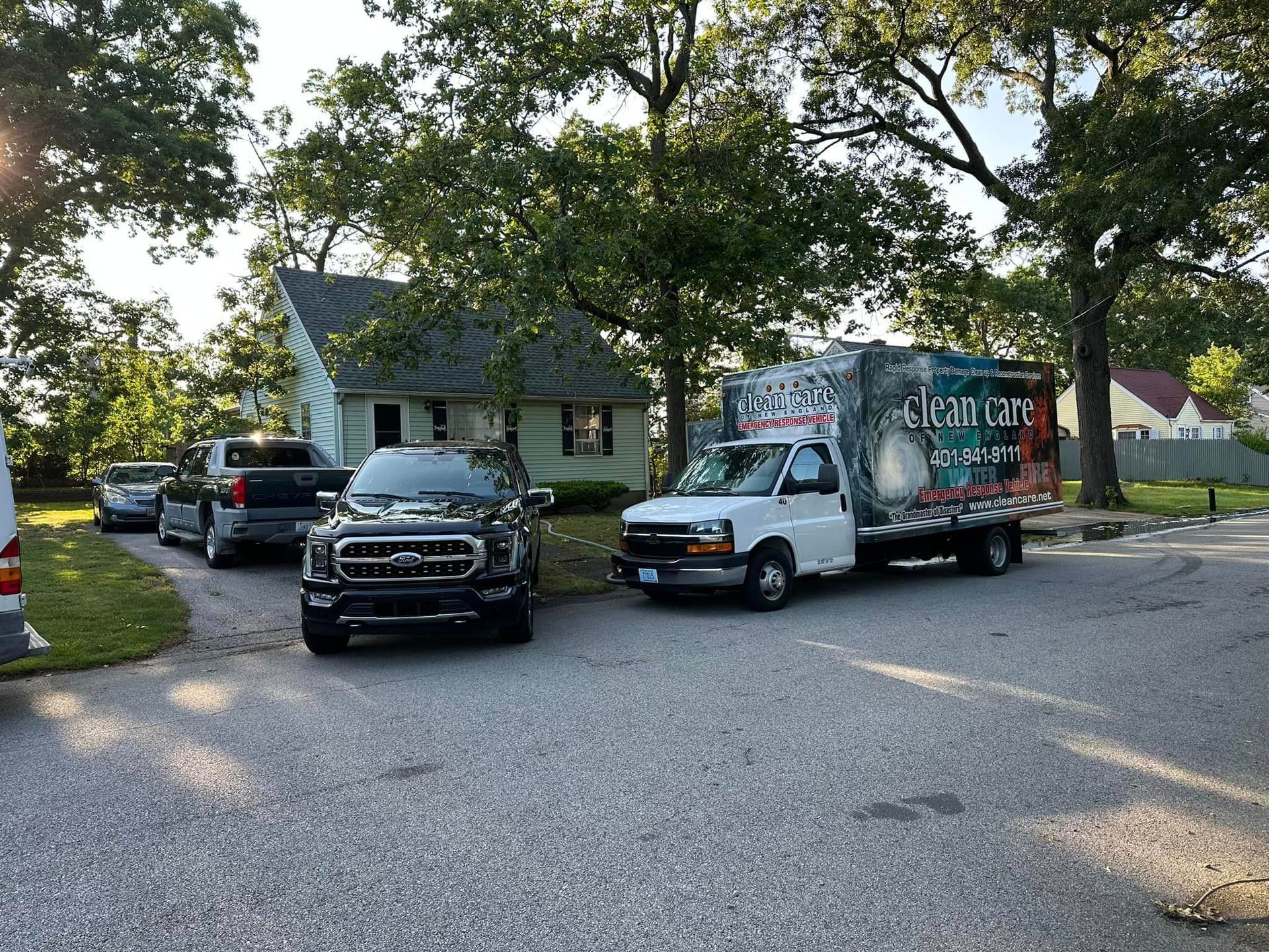 Two trucks are parked in a driveway in front of a house.