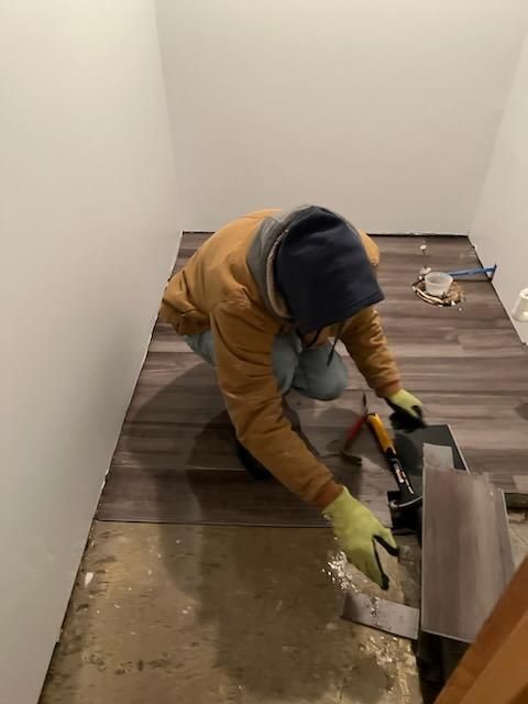 A man is kneeling on the floor in a room.