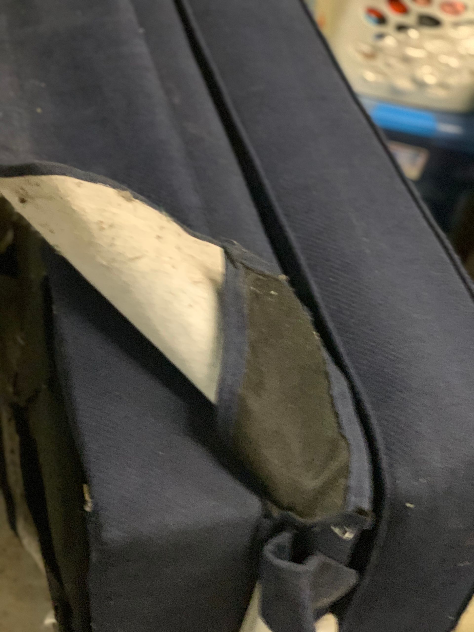 A close up of a blue couch with a hole in it