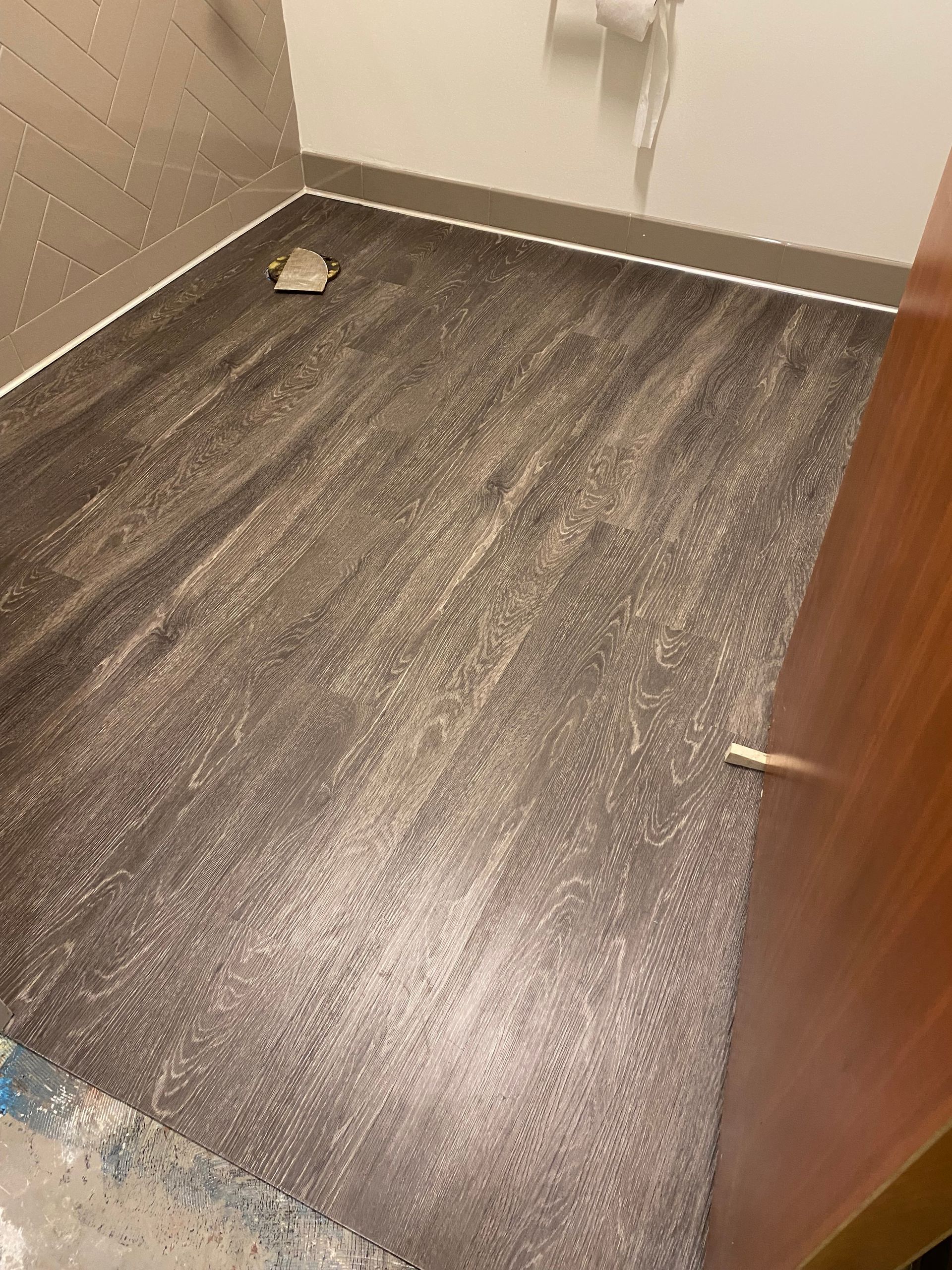 A bathroom with a wooden floor and a door.