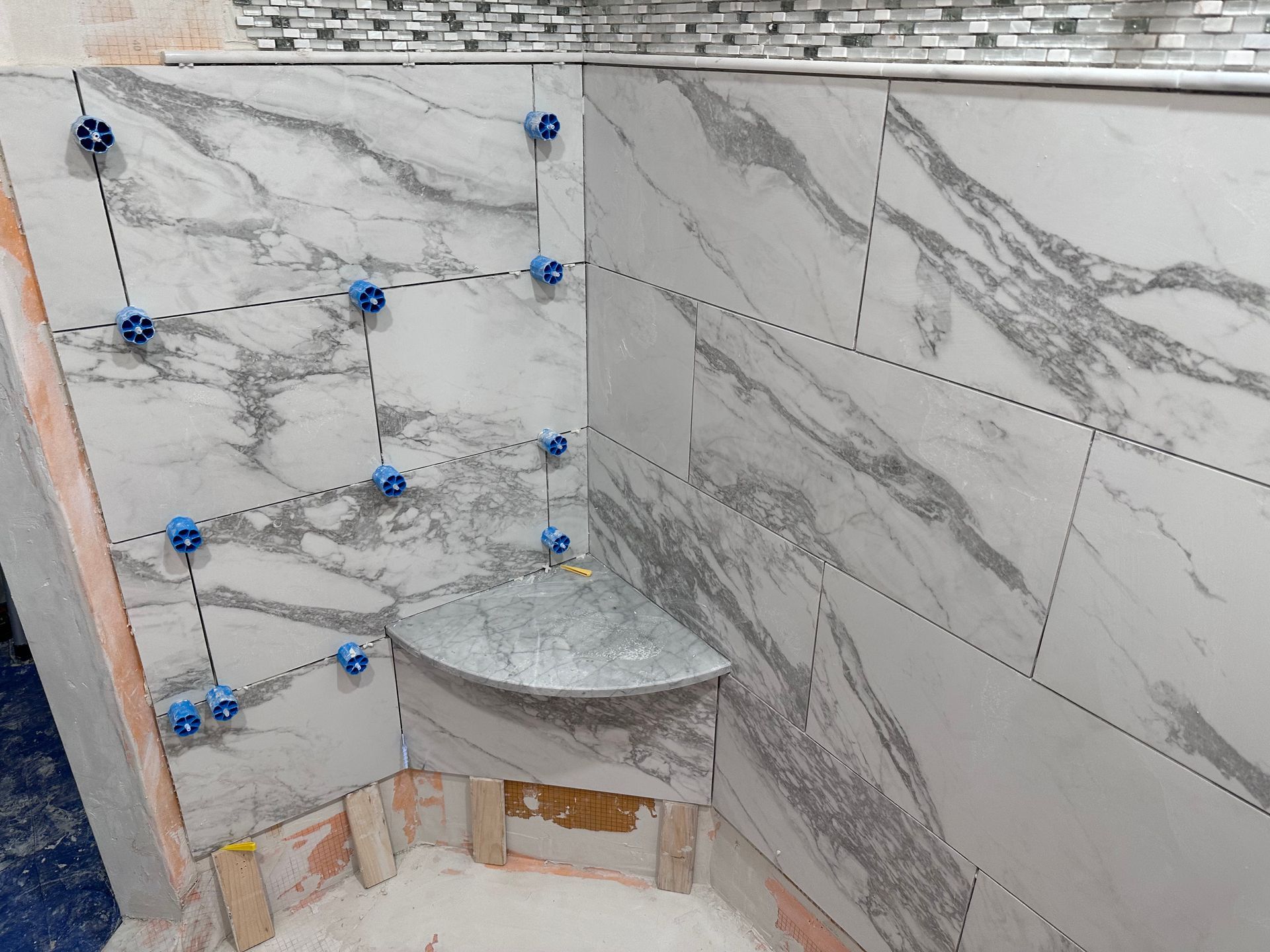 A bathroom is being remodeled with marble tiles and a shower seat.