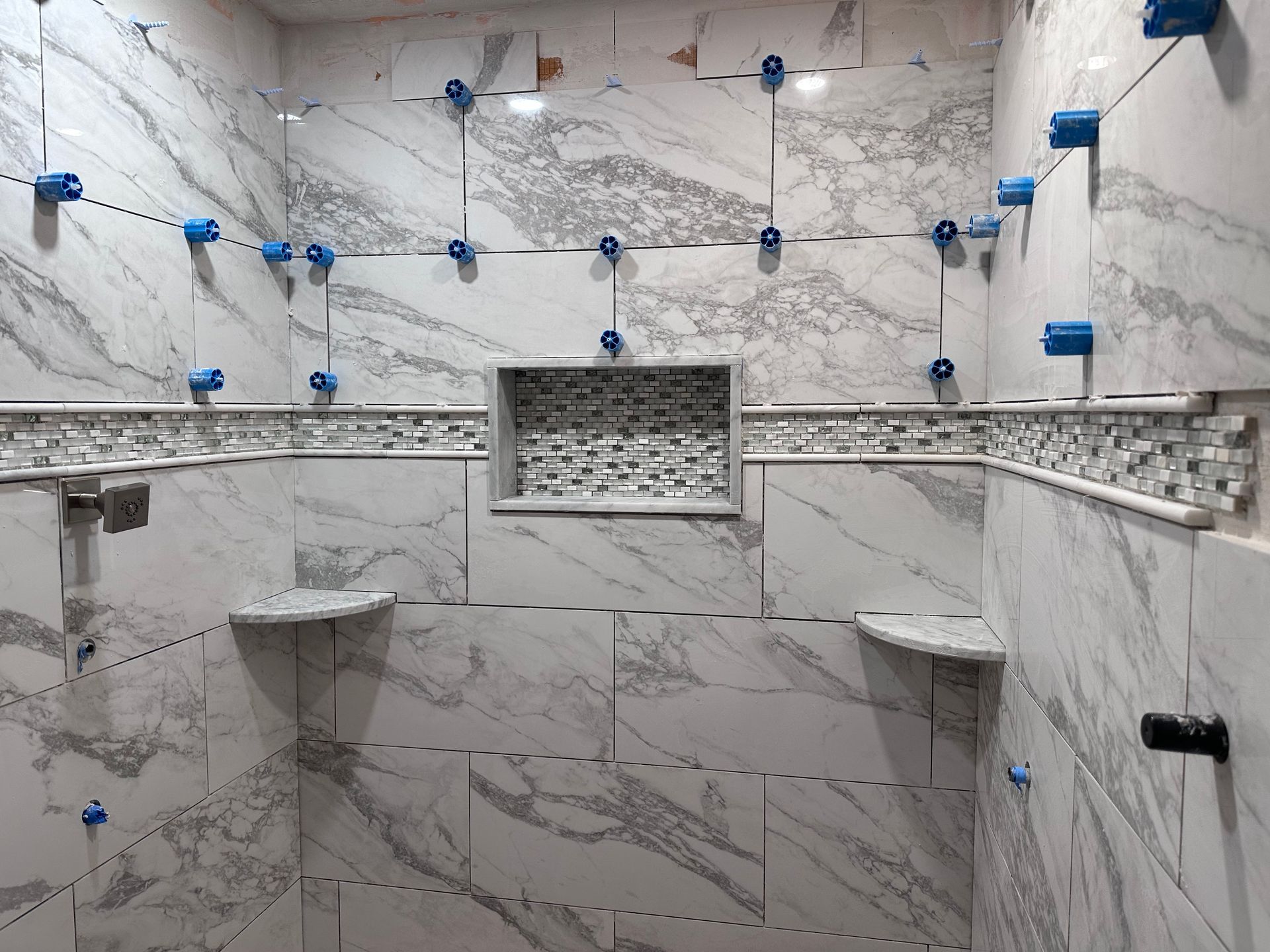 A bathroom with marble tiles being installed on the walls.
