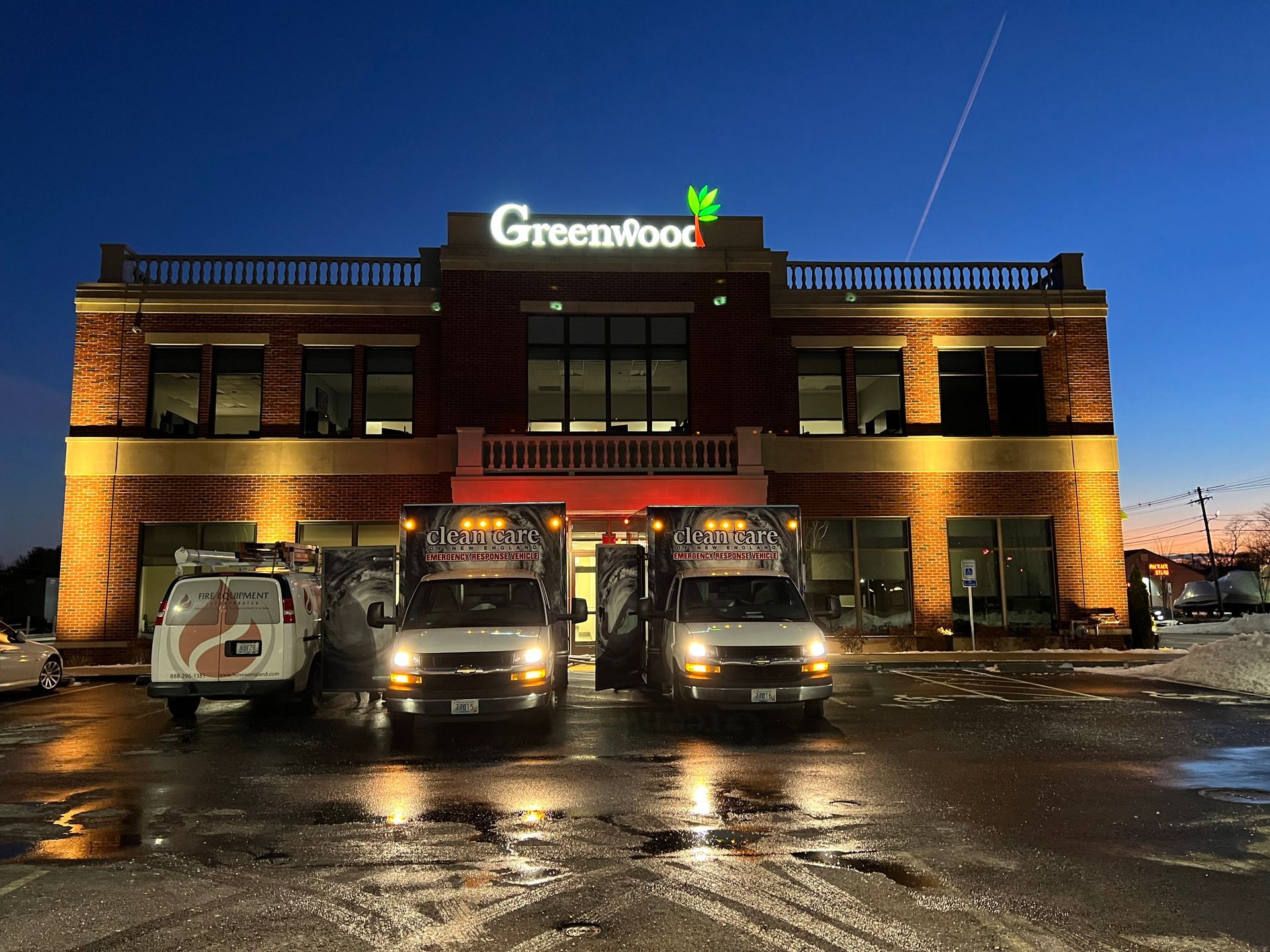 Three vans are parked in front of a building that says greenwood