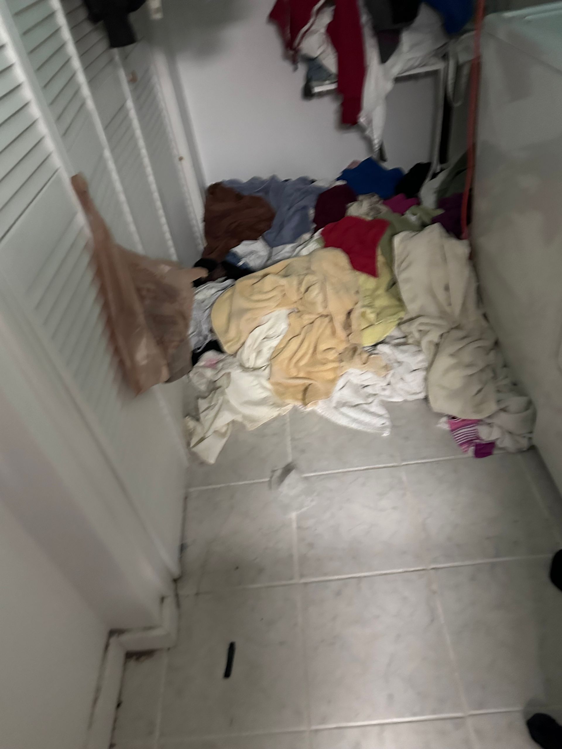 A laundry room with a lot of clothes on the floor.