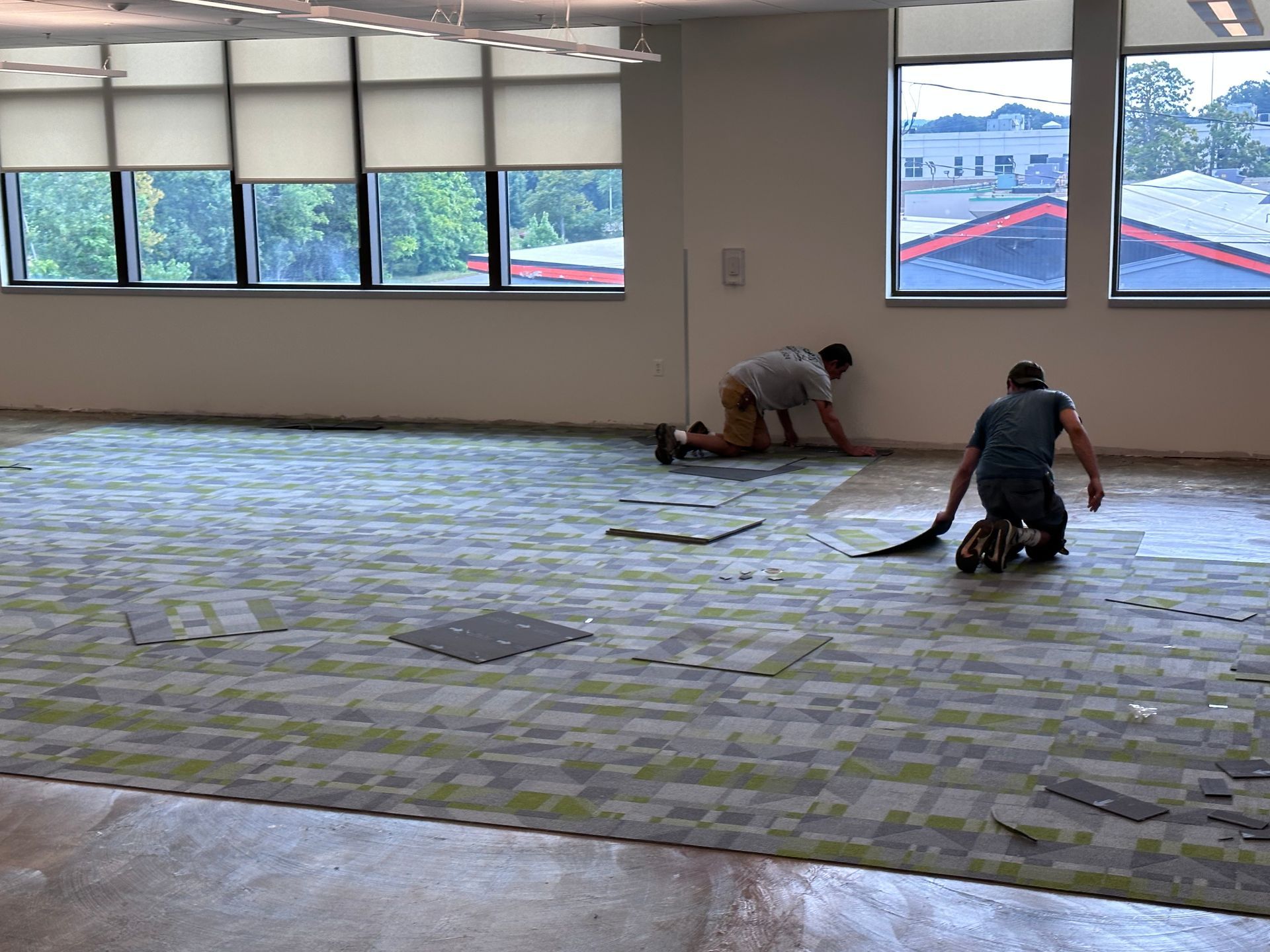 Two men are working on a carpeted floor in a large room.