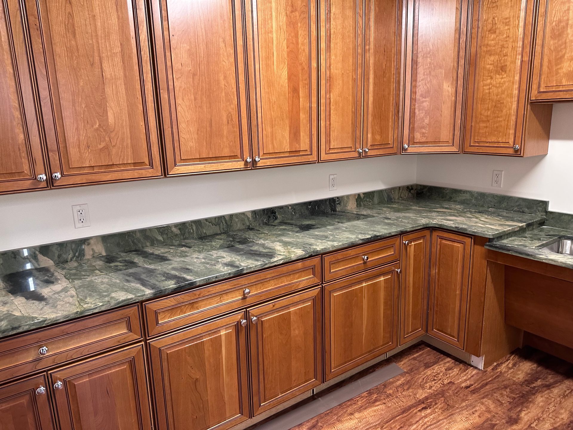 A kitchen with wooden cabinets and green granite counter tops
