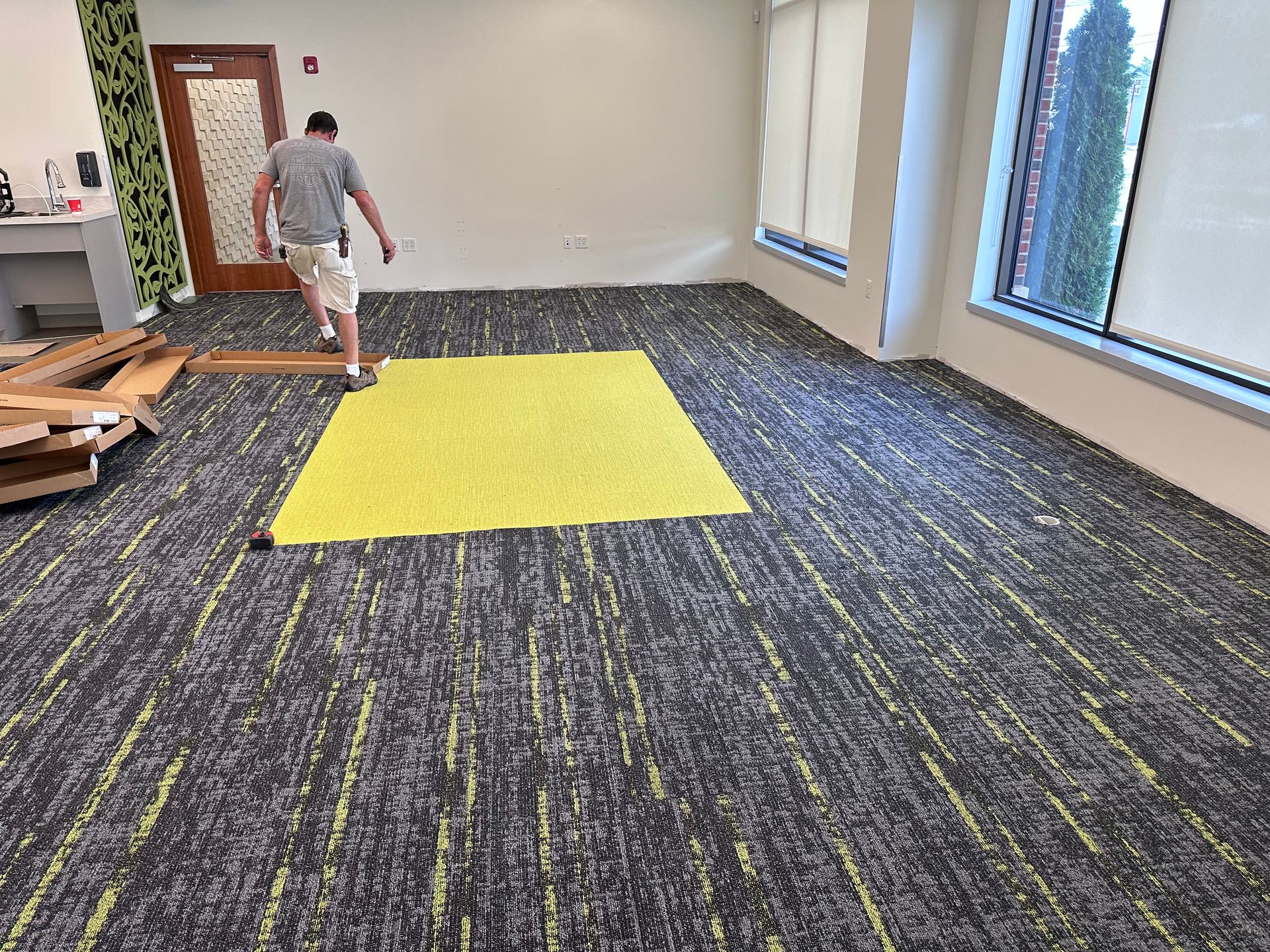 A man is standing in a room with a yellow rug on the floor.