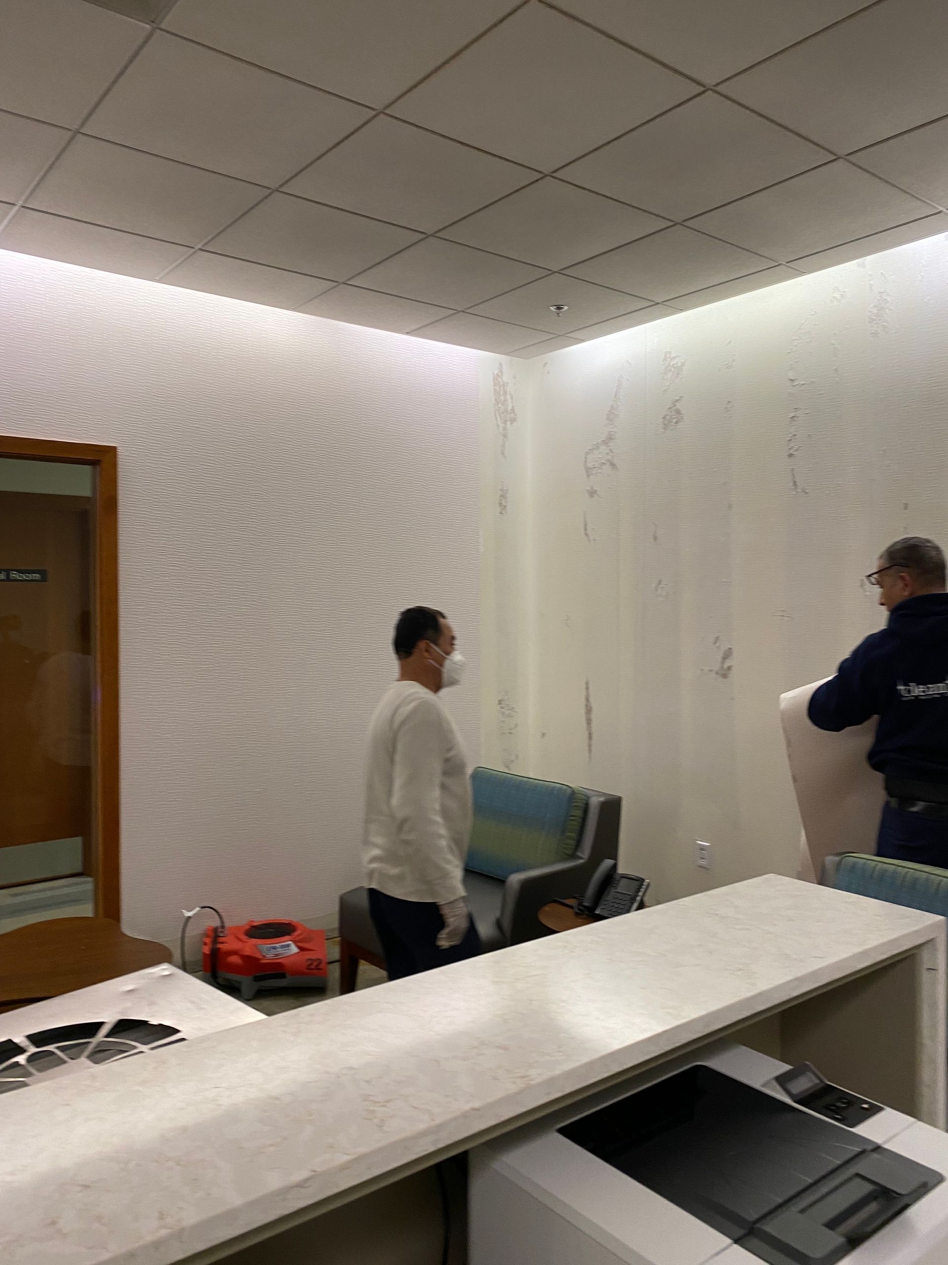 A man wearing a mask is standing in a waiting room.