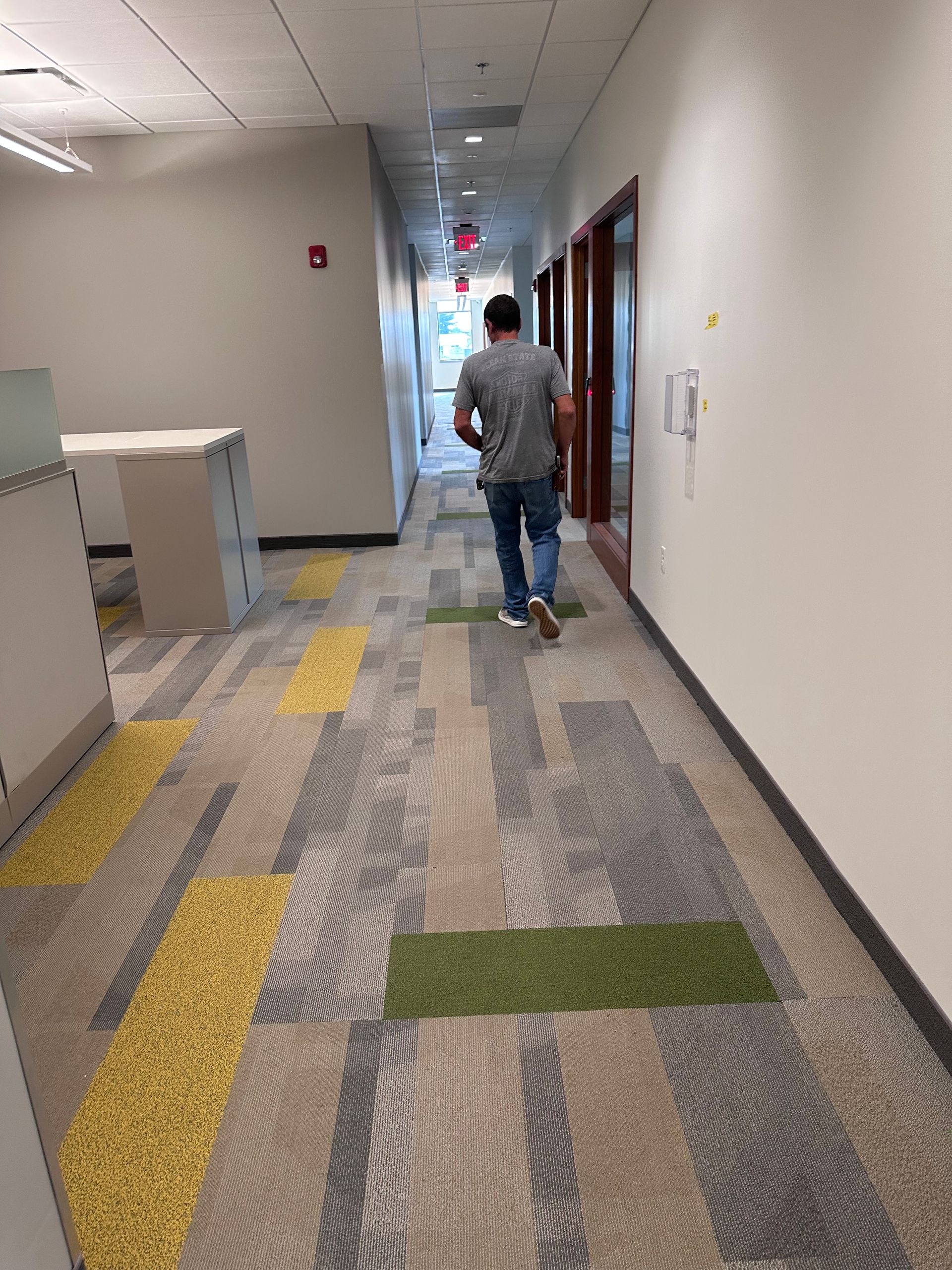 A man is walking down a hallway in an office building.
