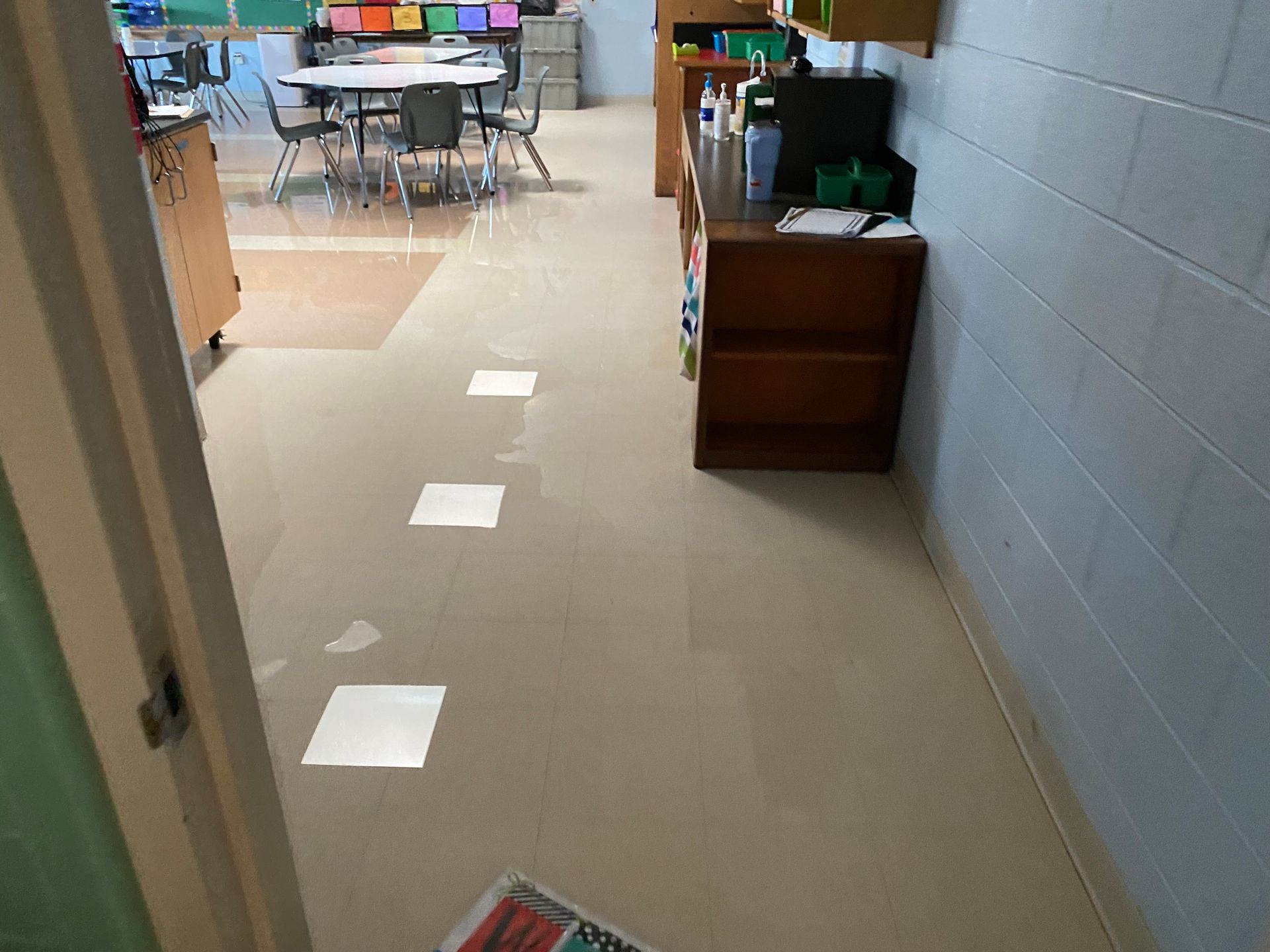 A classroom with tables and chairs and a book on the floor.