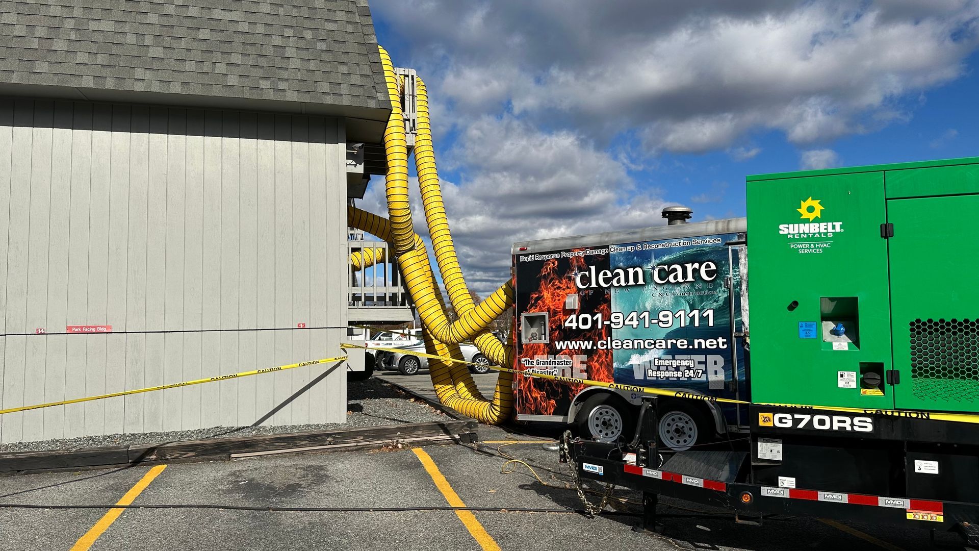 A green truck is parked in a parking lot next to a building.