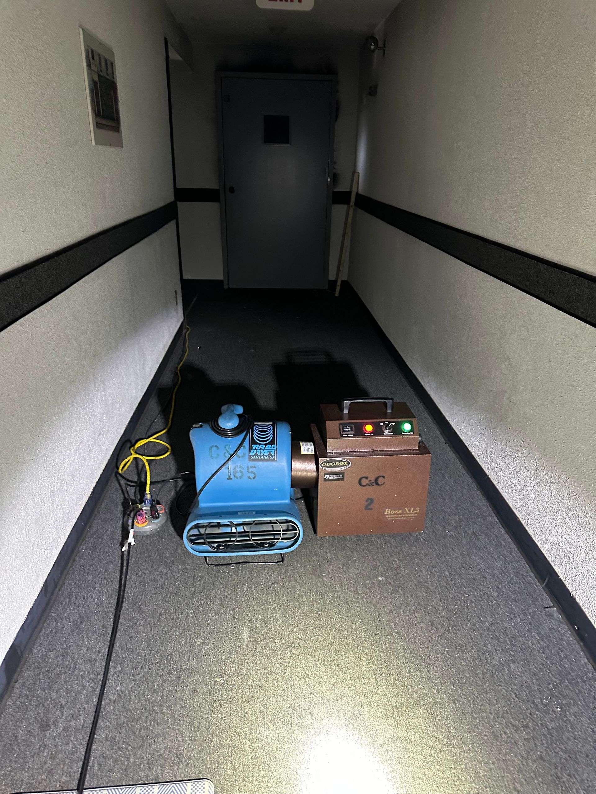A hallway with a vacuum cleaner and a box on the floor.