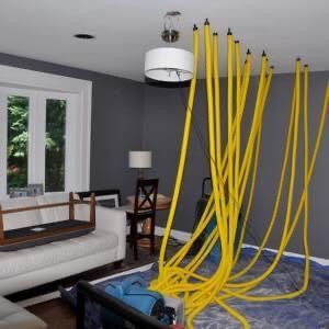 A living room with a couch and chairs and a bunch of yellow wires hanging from the ceiling