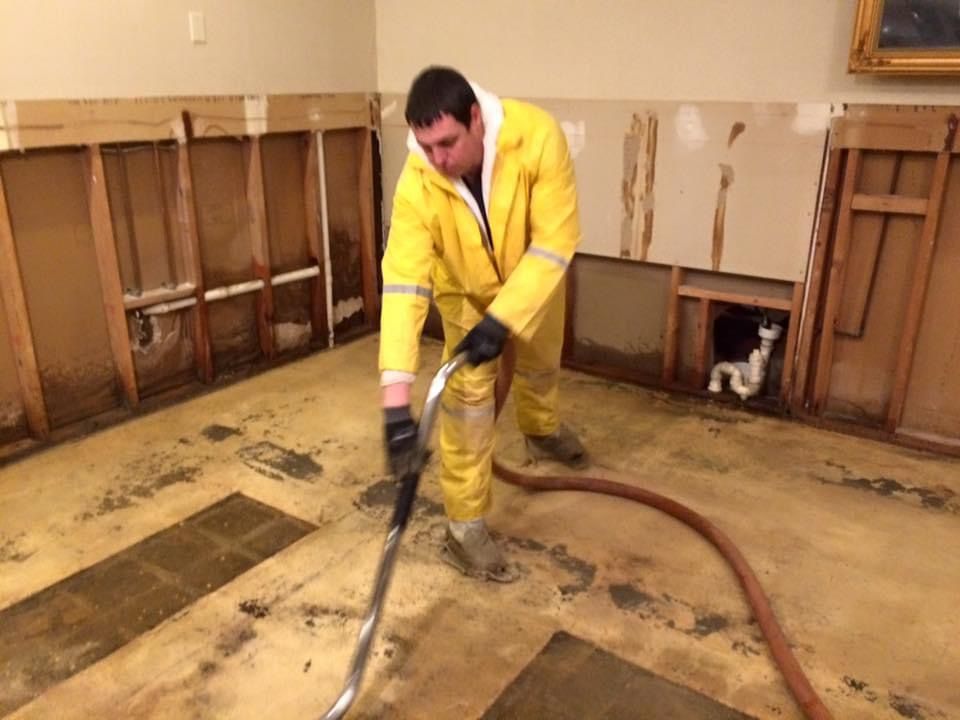 A man in a yellow suit is using a vacuum cleaner to clean a room.
