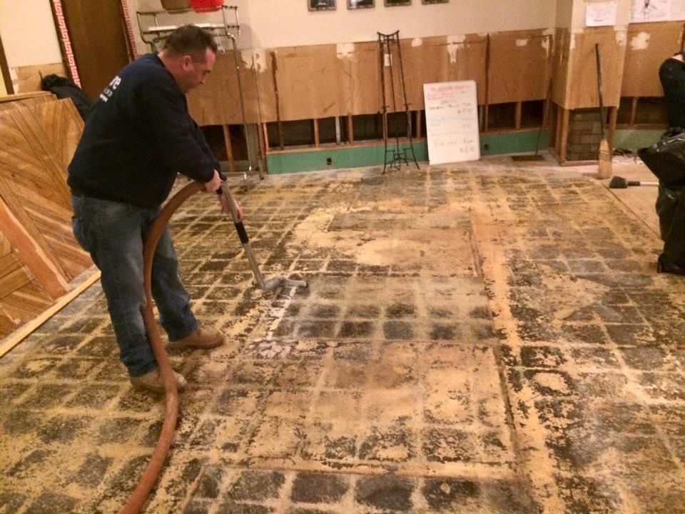 A man is using a vacuum cleaner to clean a tiled floor.