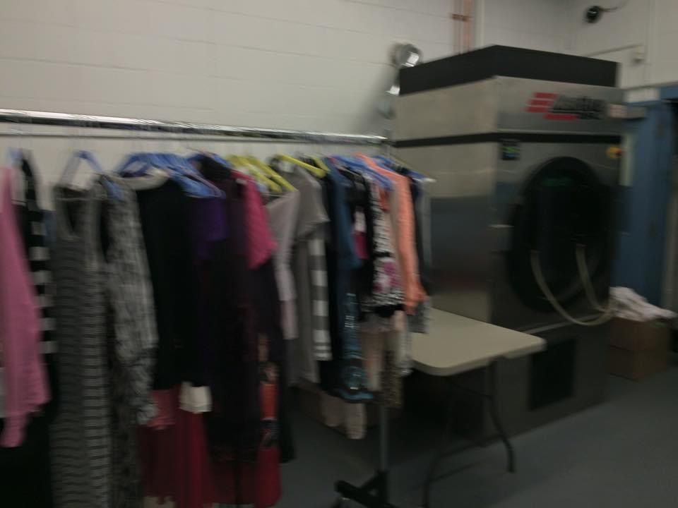 A laundry room with clothes hanging on racks and a washing machine