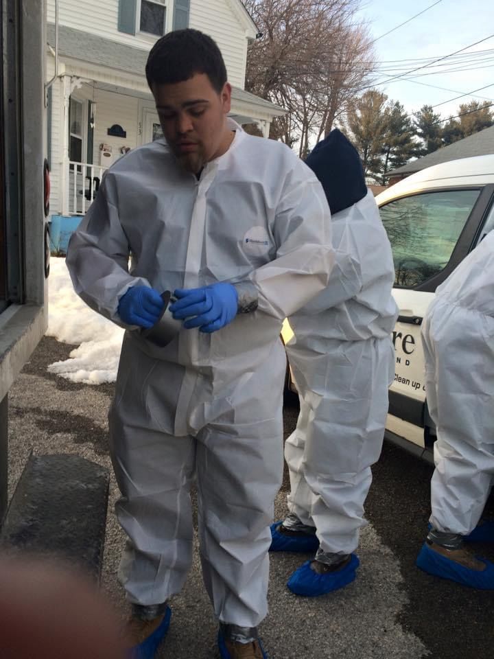 A man in a white suit is standing in front of a white van