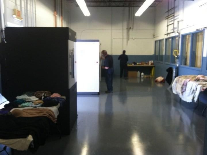 A hallway with a few beds and a man standing in the background