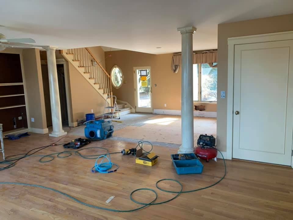 A living room with hardwood floors and a staircase in the background