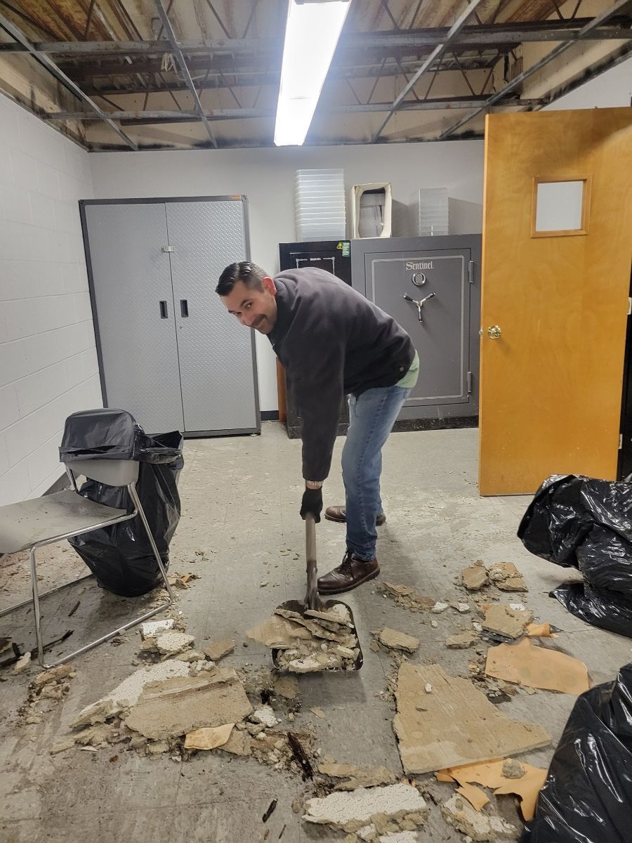 A man is using a shovel to dig a hole in the floor