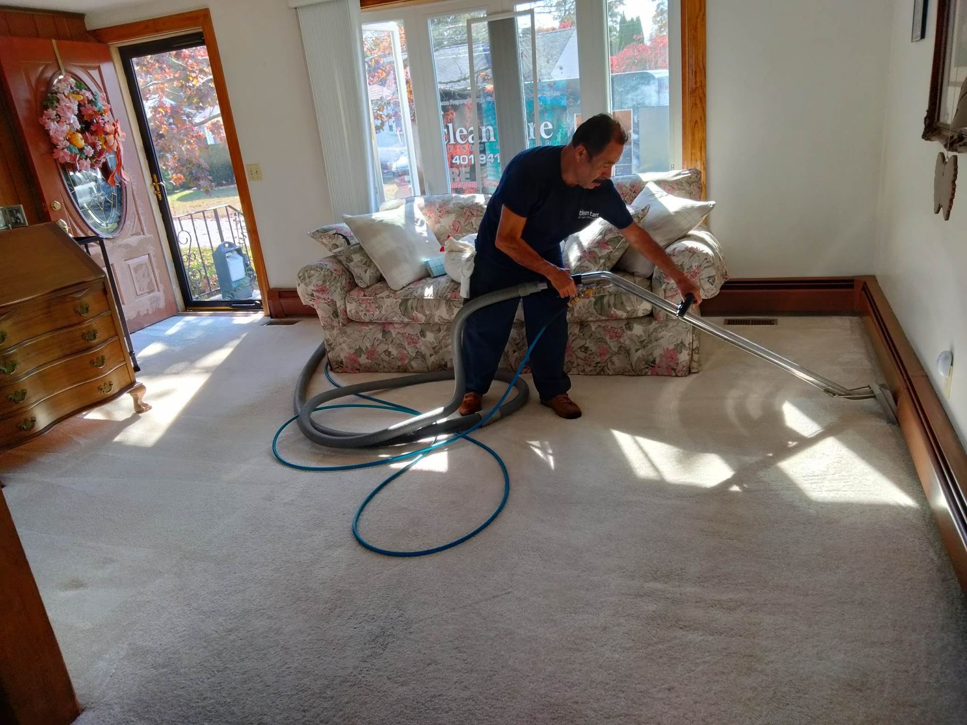 A man is using a vacuum cleaner to clean a carpet in a living room.