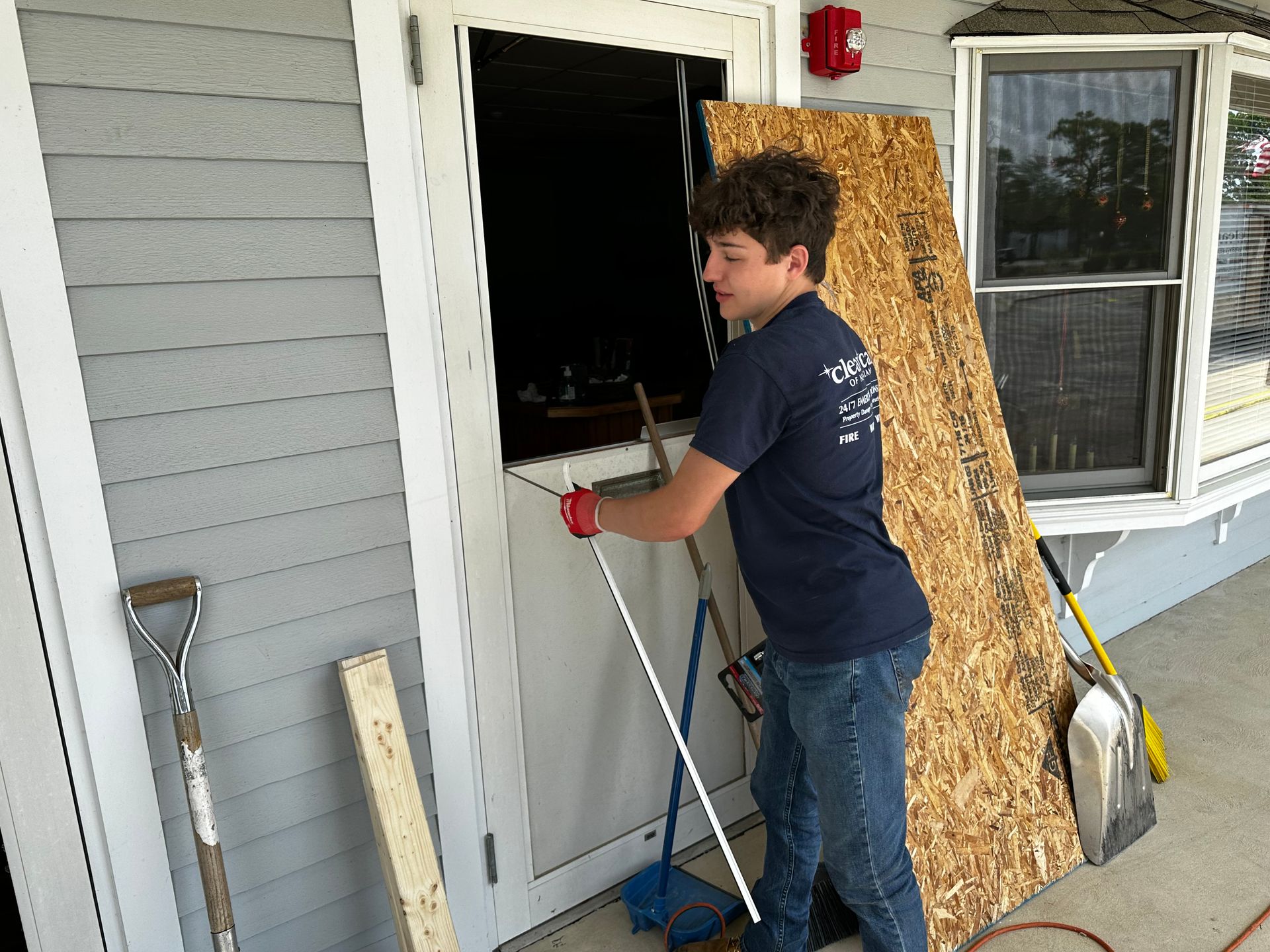 A man is standing in front of a door with a piece of plywood on it