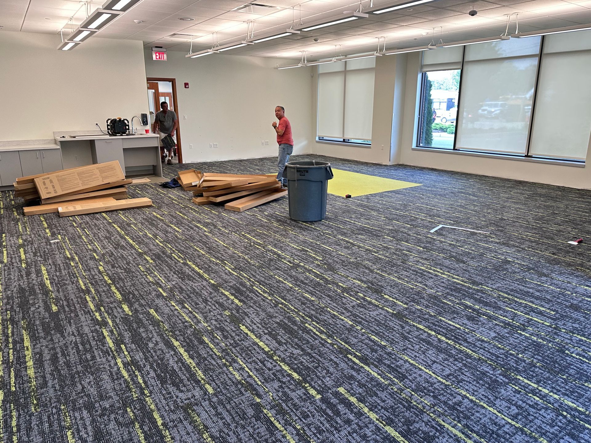 A man is standing in a large room with a carpeted floor.