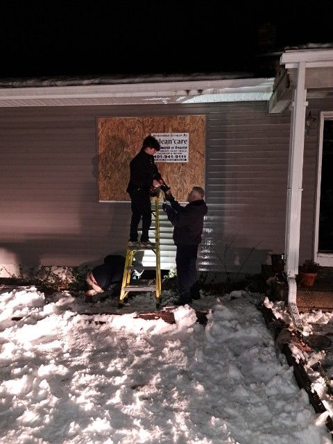 A couple of men standing on a ladder in front of a house