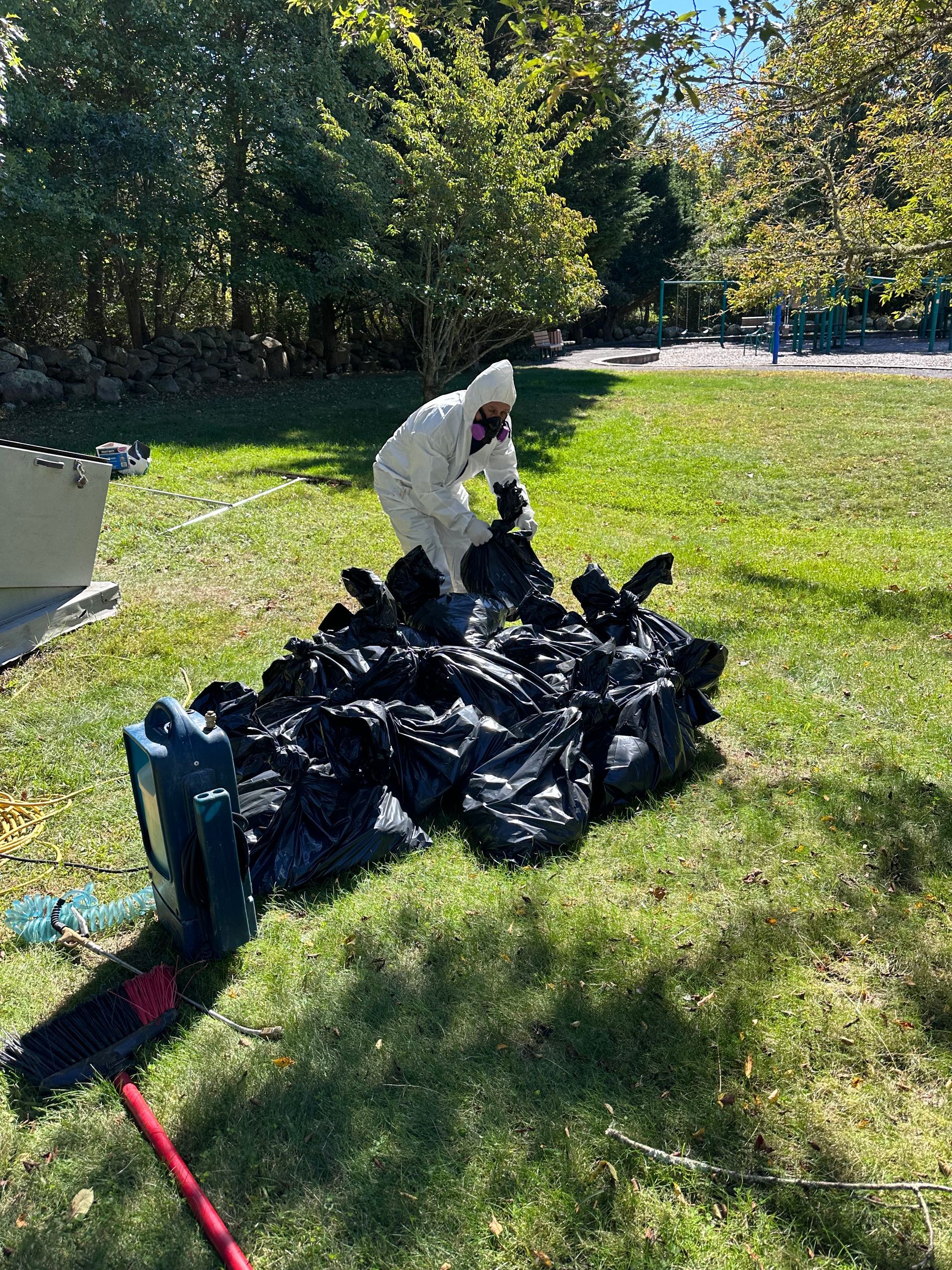 A man in a white suit is standing next to a pile of trash bags.