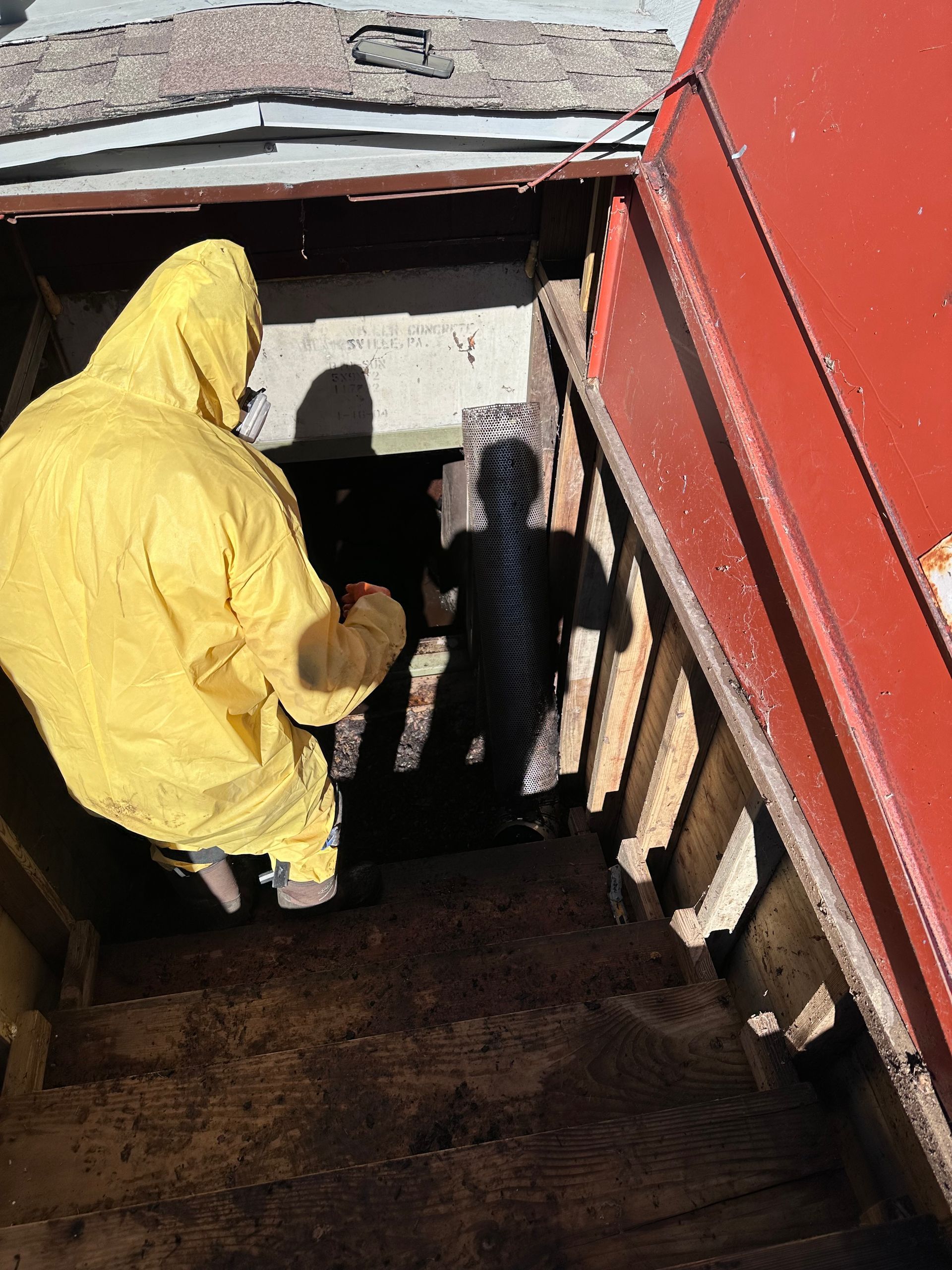 A man in a yellow protective suit is walking through a doorway.