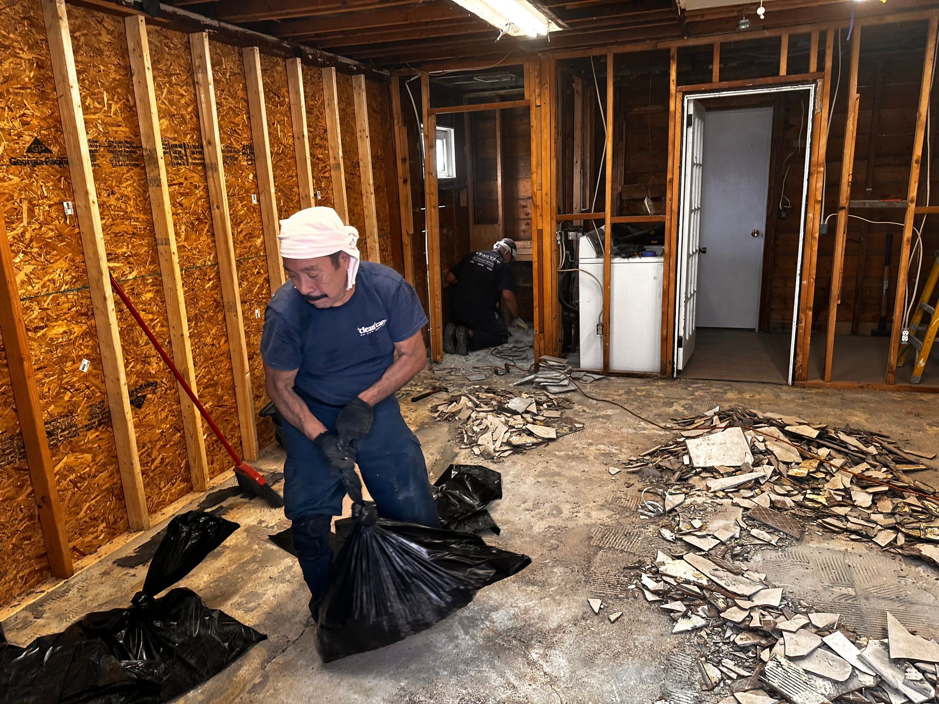 A man is cleaning the floor of a basement with a broom.