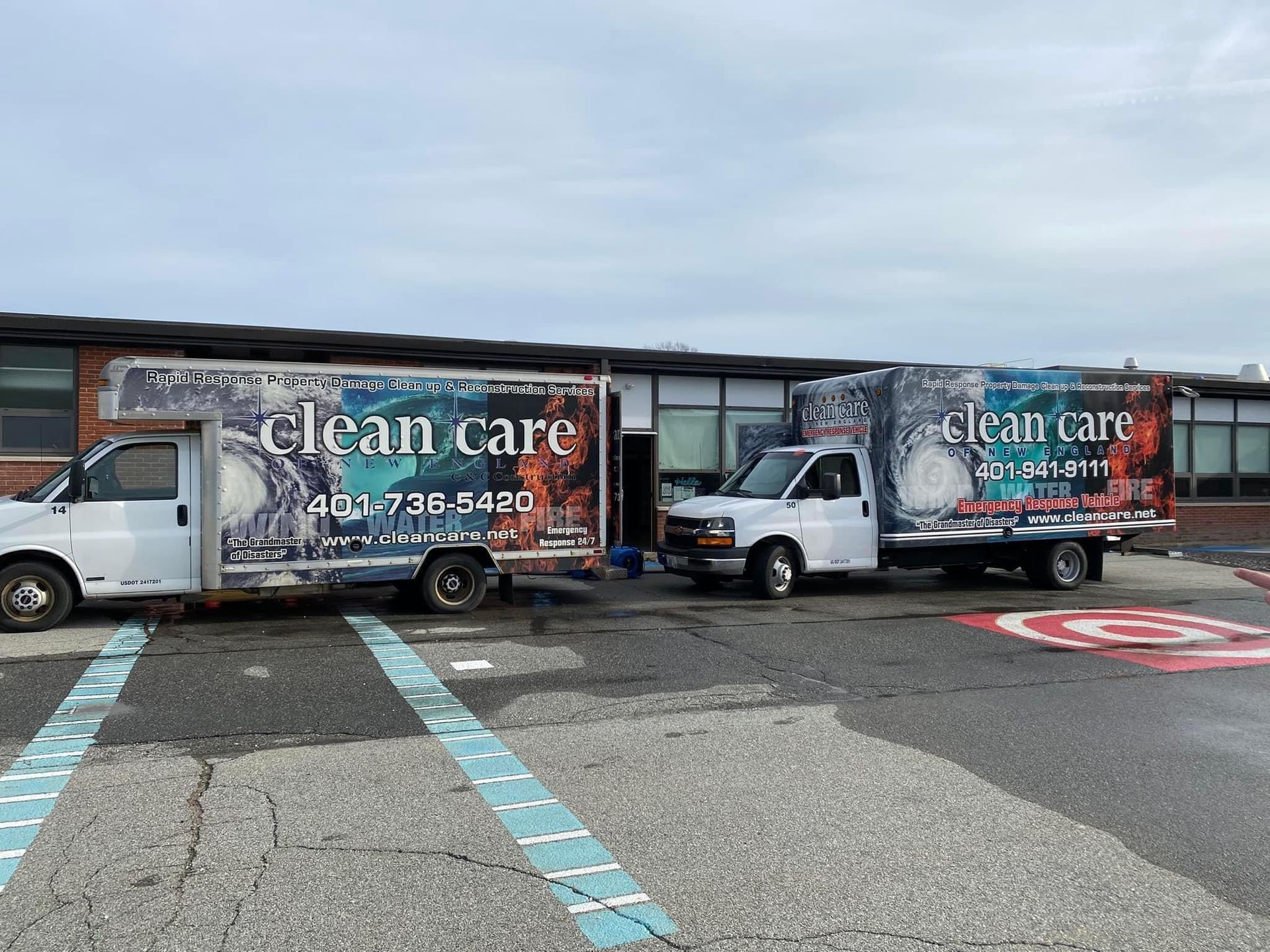 Two clean care trucks are parked in front of a building.