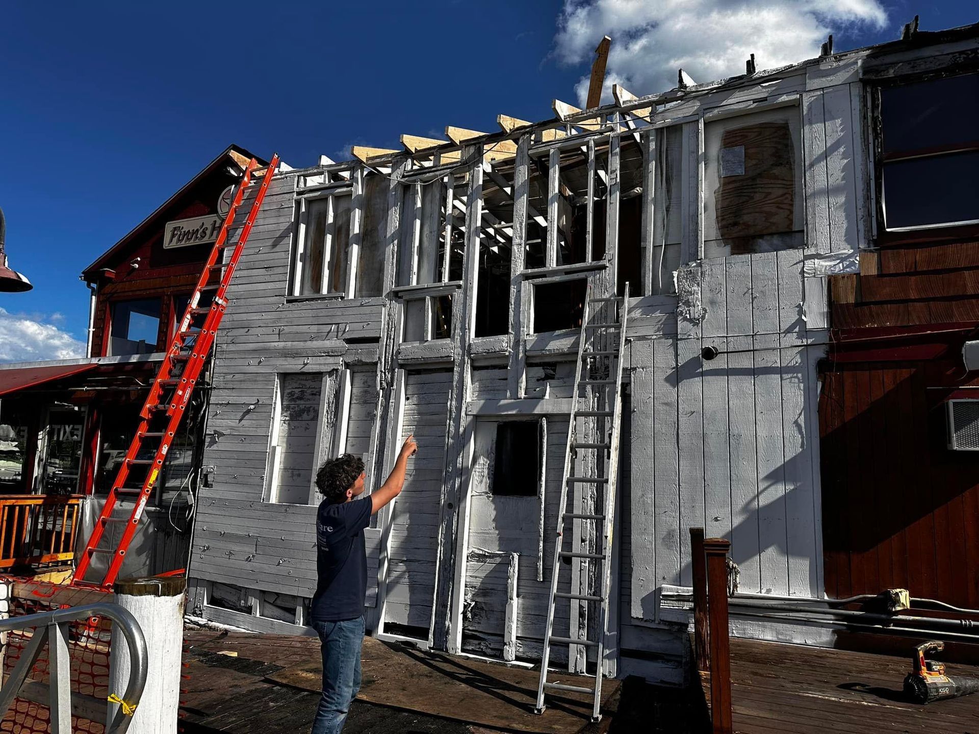 A man is standing in front of a building with a ladder attached to it.