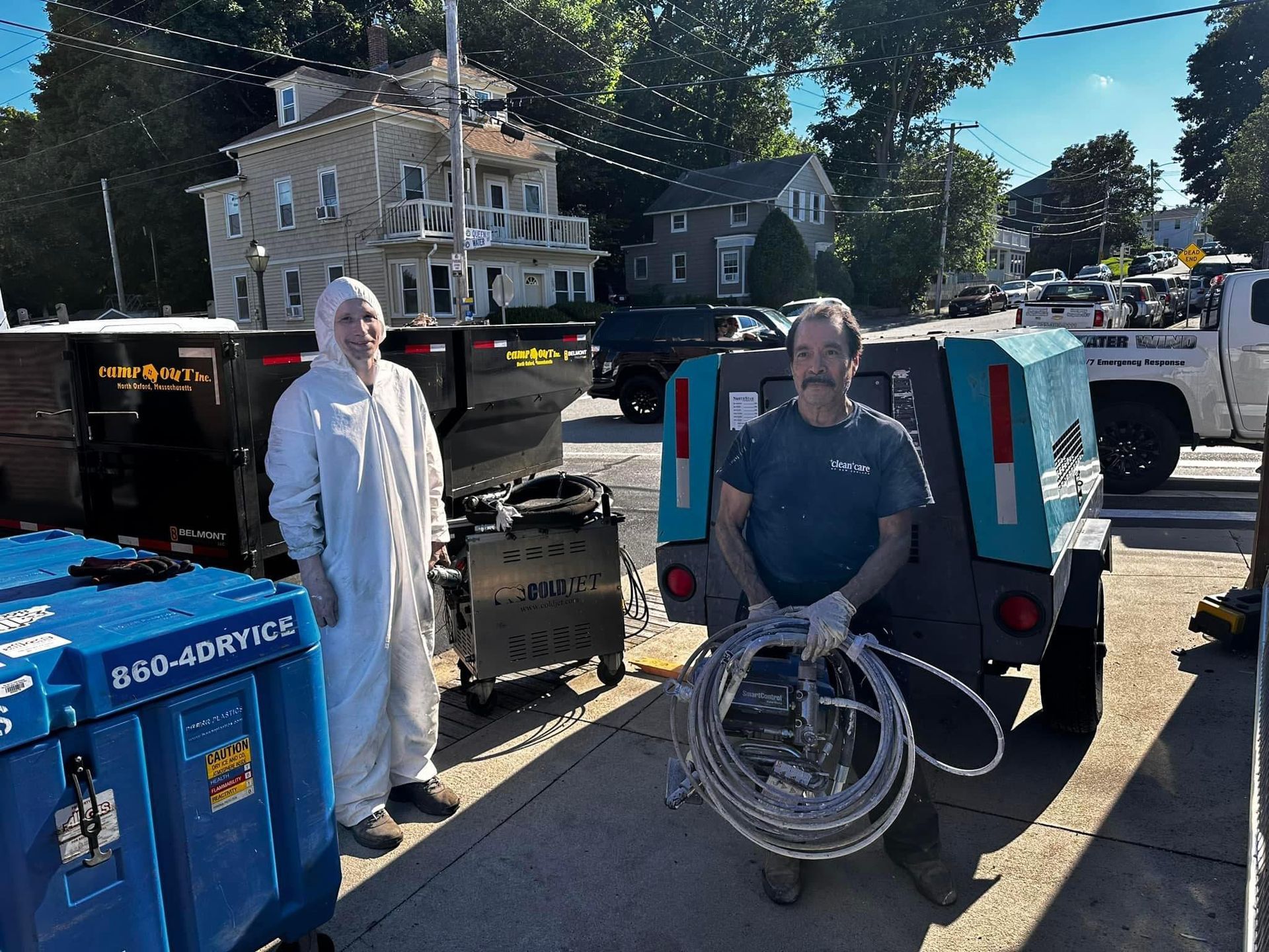 Two men standing next to a trailer that says 800-joatrice