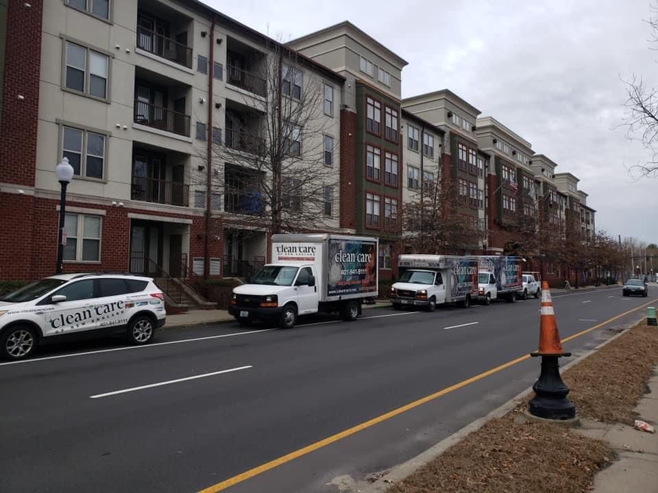 A row of trucks are parked on the side of the road in front of a building.