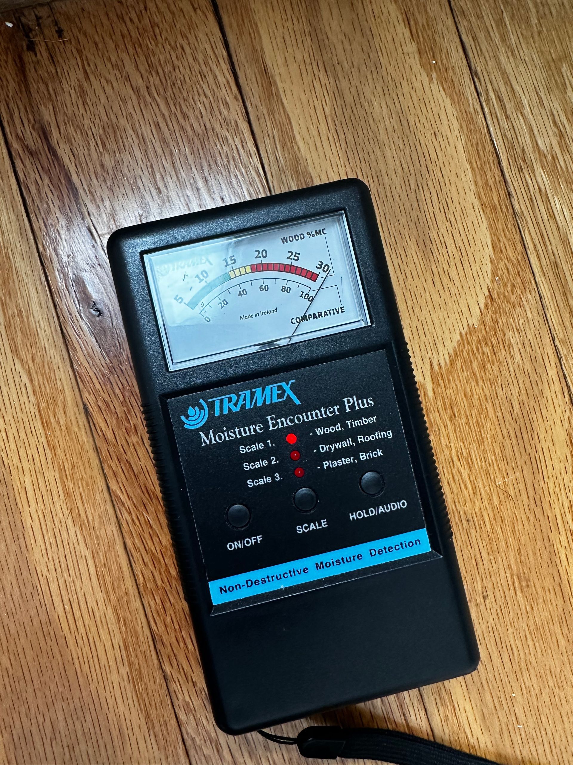 A moisture meter is sitting on a wooden floor.